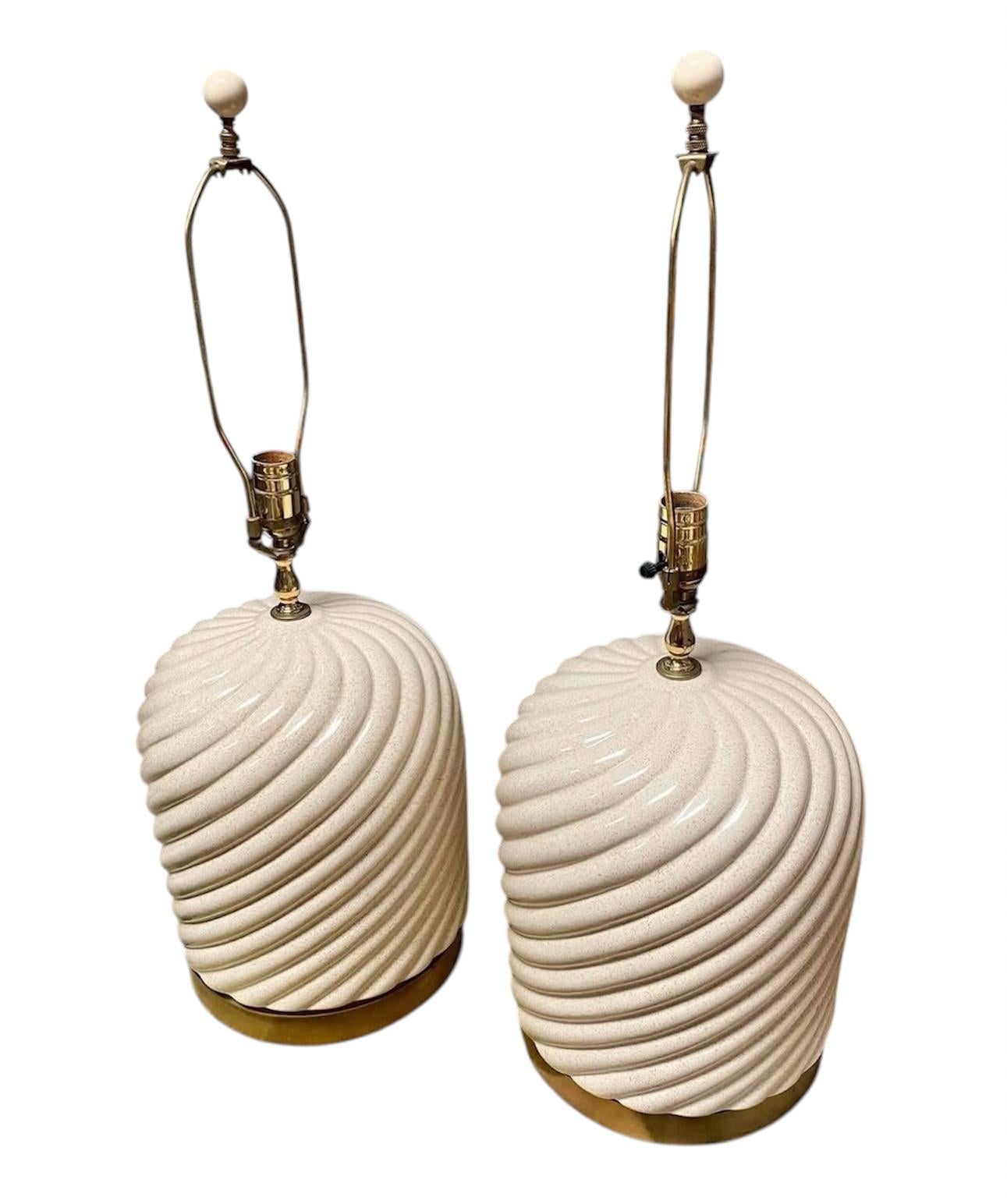 These Tommaso Barbi lamps exhibit a distinctive sculptural design, featuring a ceramic base with a textured, swirling pattern that gives them a dynamic, almost fluid appearance. The bases are finished in an off-white or cream color with a subtle