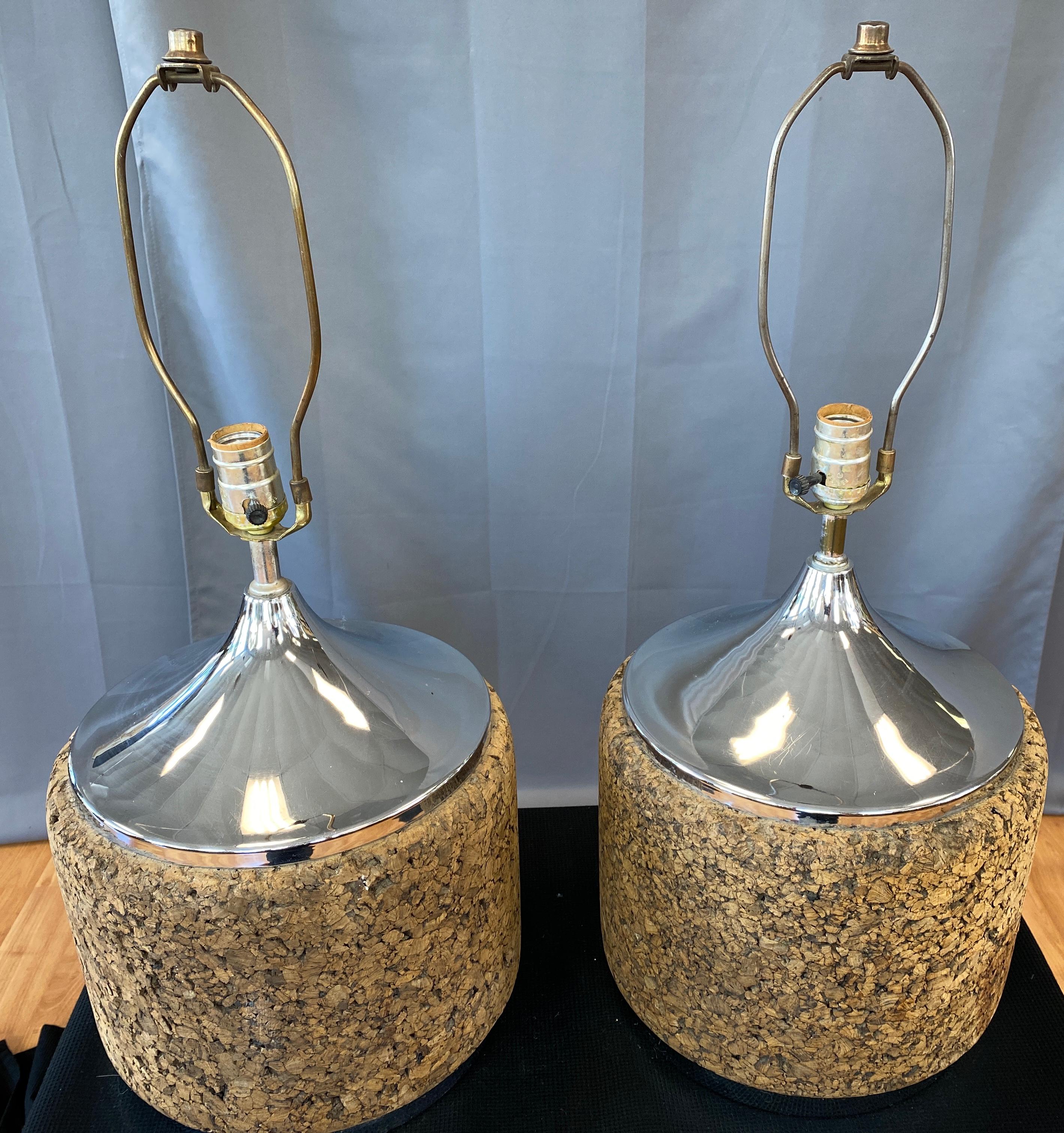 A great looking pair of classic 1970s MOD Cork lamps,
Many pieces of cork formed into a nice barrel shape, with a chromed metal holding all together from its top and bottom.

17 inches top of socket, 35 1/2 in circumference, over all below.