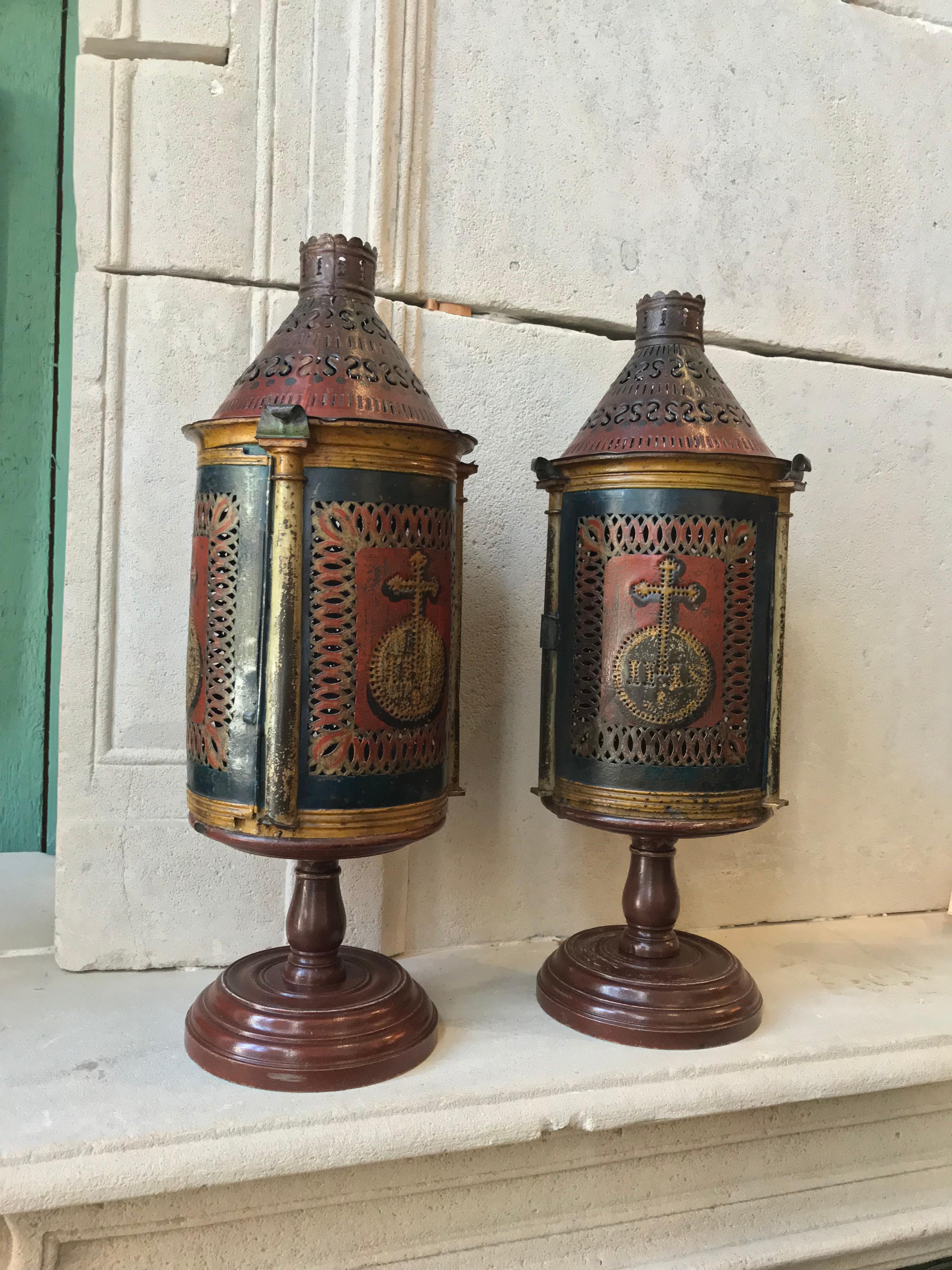 Beautiful pair 19th century continental central European candle lanterns
candleholder lamps, decorative object 
Made of handcut patterned tole and painted with very subtle red blue green and gold color and mounted on a hand carved painted round wood