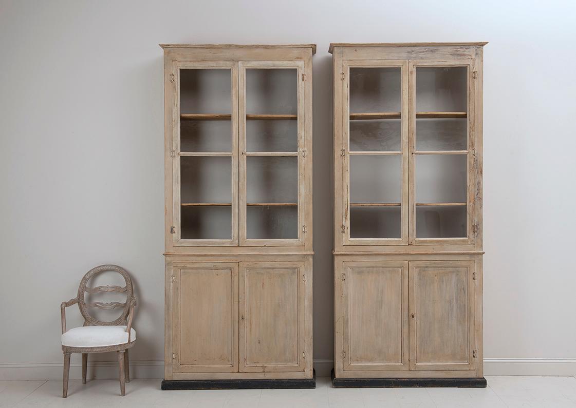 A pair of 19th c. French Directoire style bibliothèque bookcases or vitrines made of fir wood with original glass and seven adjustable shelves in the top and bottom sections (rack and pinion system). Original patina. The backs are open. The shelves