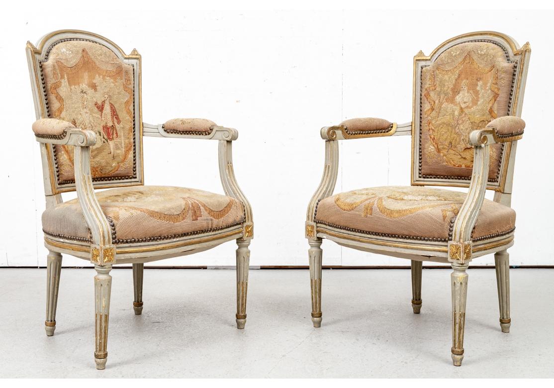 Scrolled arm ends and ribbed curved supports ending in gilt rosettes on the skirt rails. Raised on tapering fluted cylindrical legs. Upholstered in fine pale tone petit point featuring a courting couple in a landscape on one, and a lady in a garden