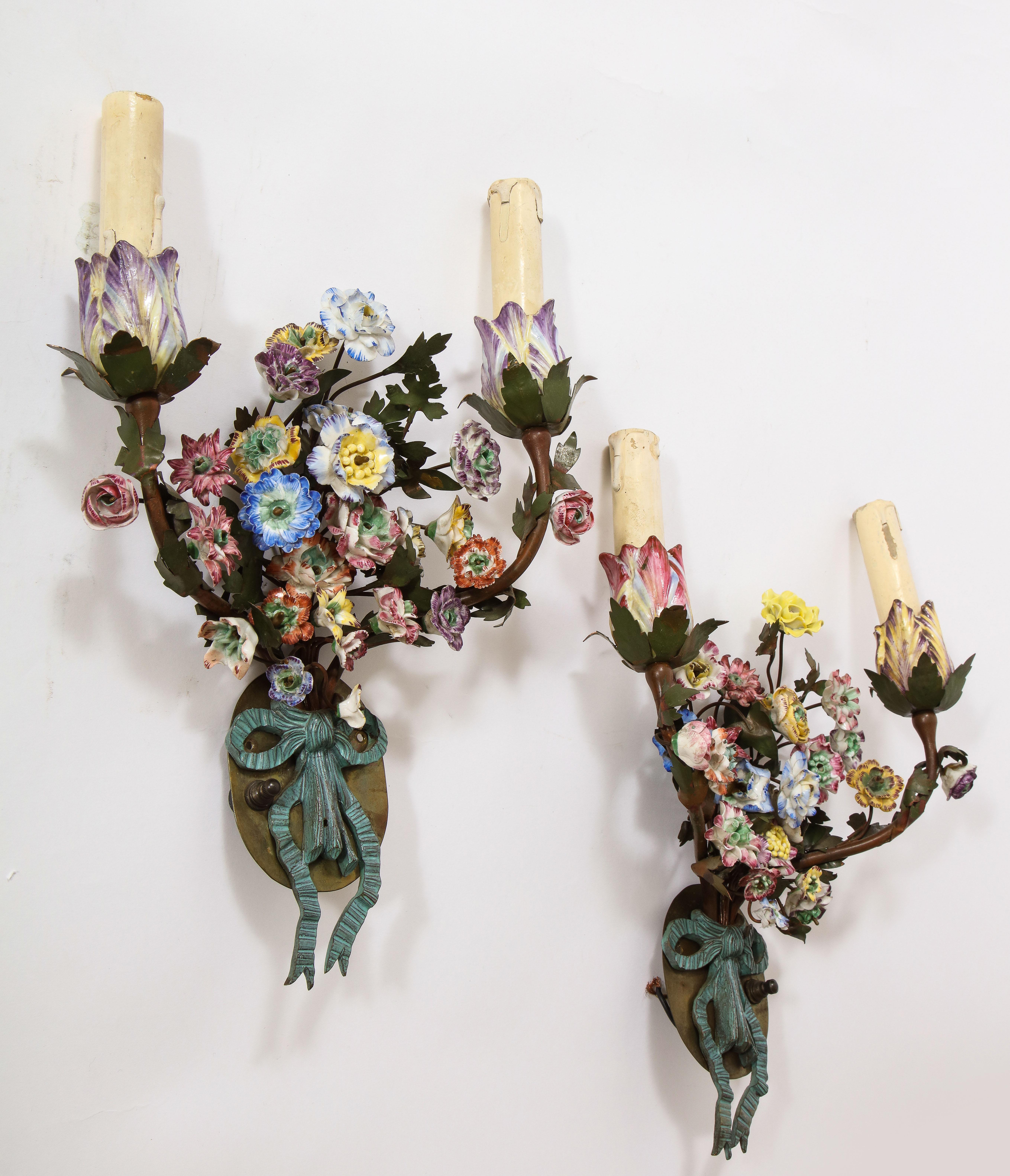 Magnifica coppia di lampade a doppia luce in tole e porcellana francese del XIX secolo con fiori in porcellana policroma.  Questa coppia di applique francesi a due luci è realizzata con fiori di porcellana montati su tole. Le applique sono