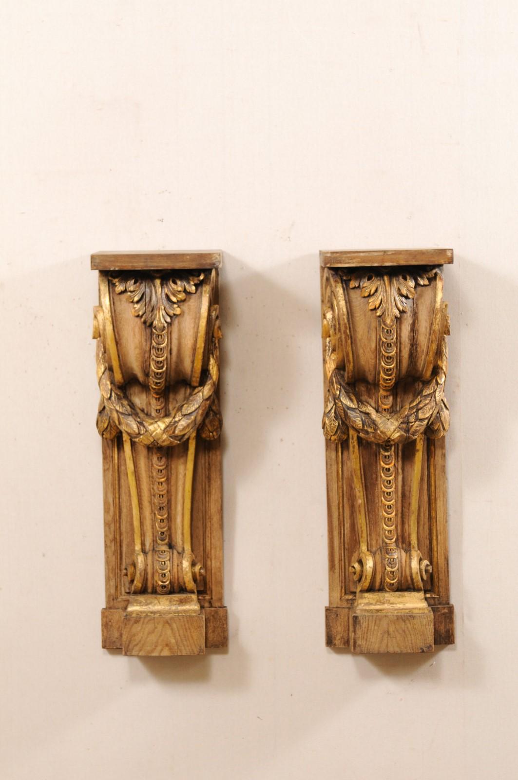 A French pair of carved and giltwood corbels from the 19th century. These antique decorative wall brackets from France each feature exquisite volute carved bodies with an acanthus leaf rolling down it's topside, and garland swag draped across it's