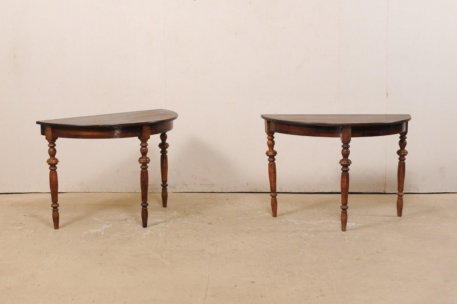 A pair of 19th century Swedish carved wood demilune tables. This pair of antique fir wood demilune tables from Sweden feature half moon tops over rounded aprons, which are raised upon three beautifully turned legs. The medium dark finish has a nice