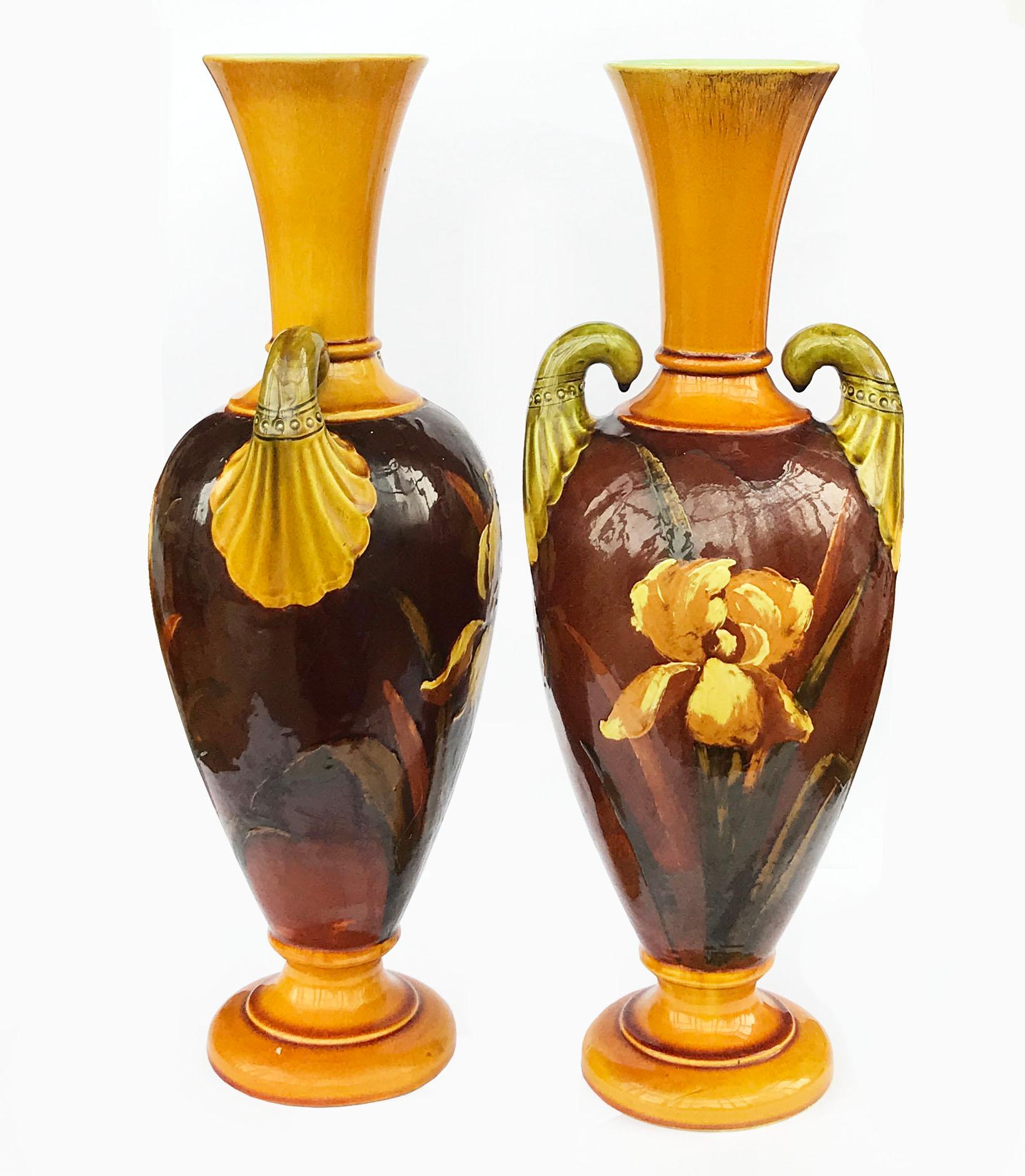 An excellent quality imposing pair of 19th century Arts & Crafts vases, circa 1890
Each with twin Egyptian inspired handles, decorated with amber colored large irises painted in the barbotine technique and all against a body of browns and ochres
