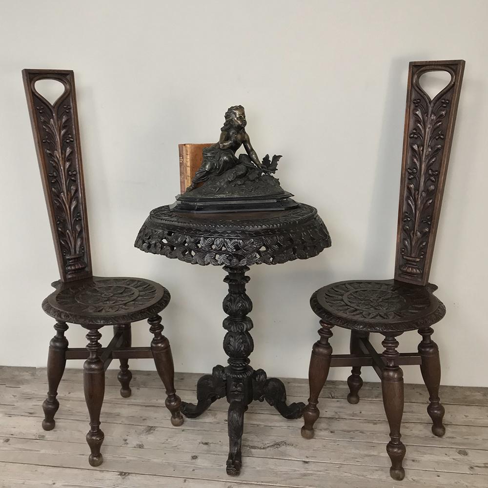 Pair of 19th century Black Forest chairs are wonderfully decorative, and great for those that entertain in style! Each has been lavished with sculpted brilliance down the entire backsplat and on the entire rounded seat surface. Four turned legs