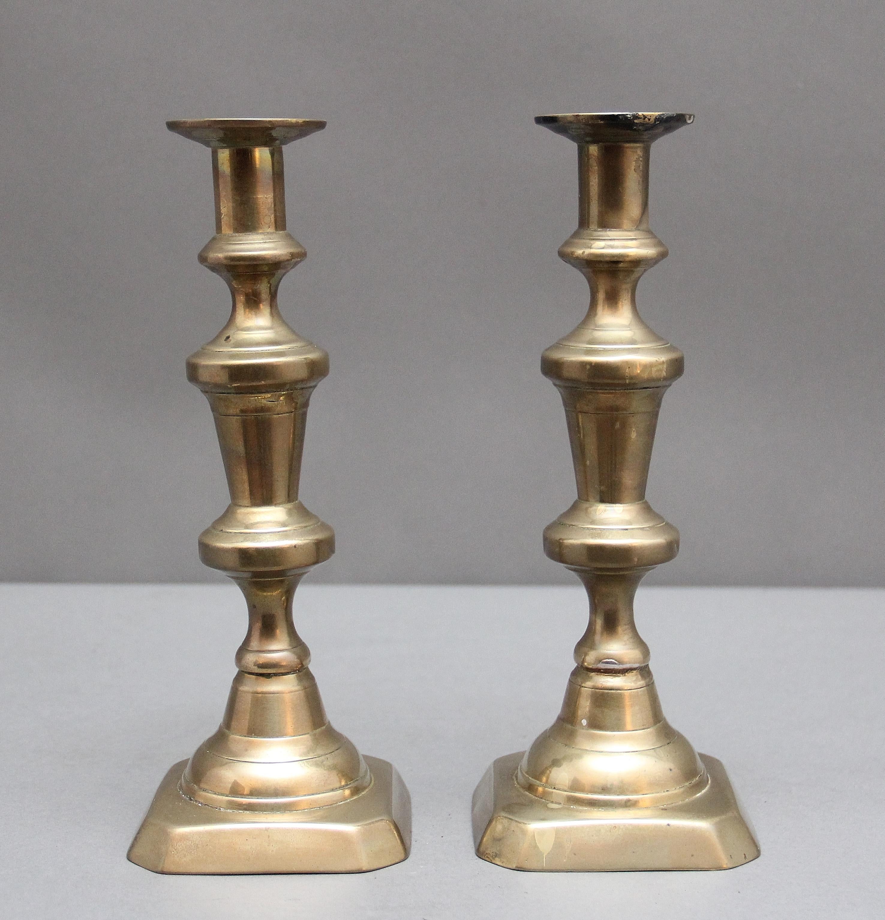 Coppia di candelieri in ottone del XIX secolo, con colonne tornite e sagomate sollevate su una base quadrata.  Circa 1860.