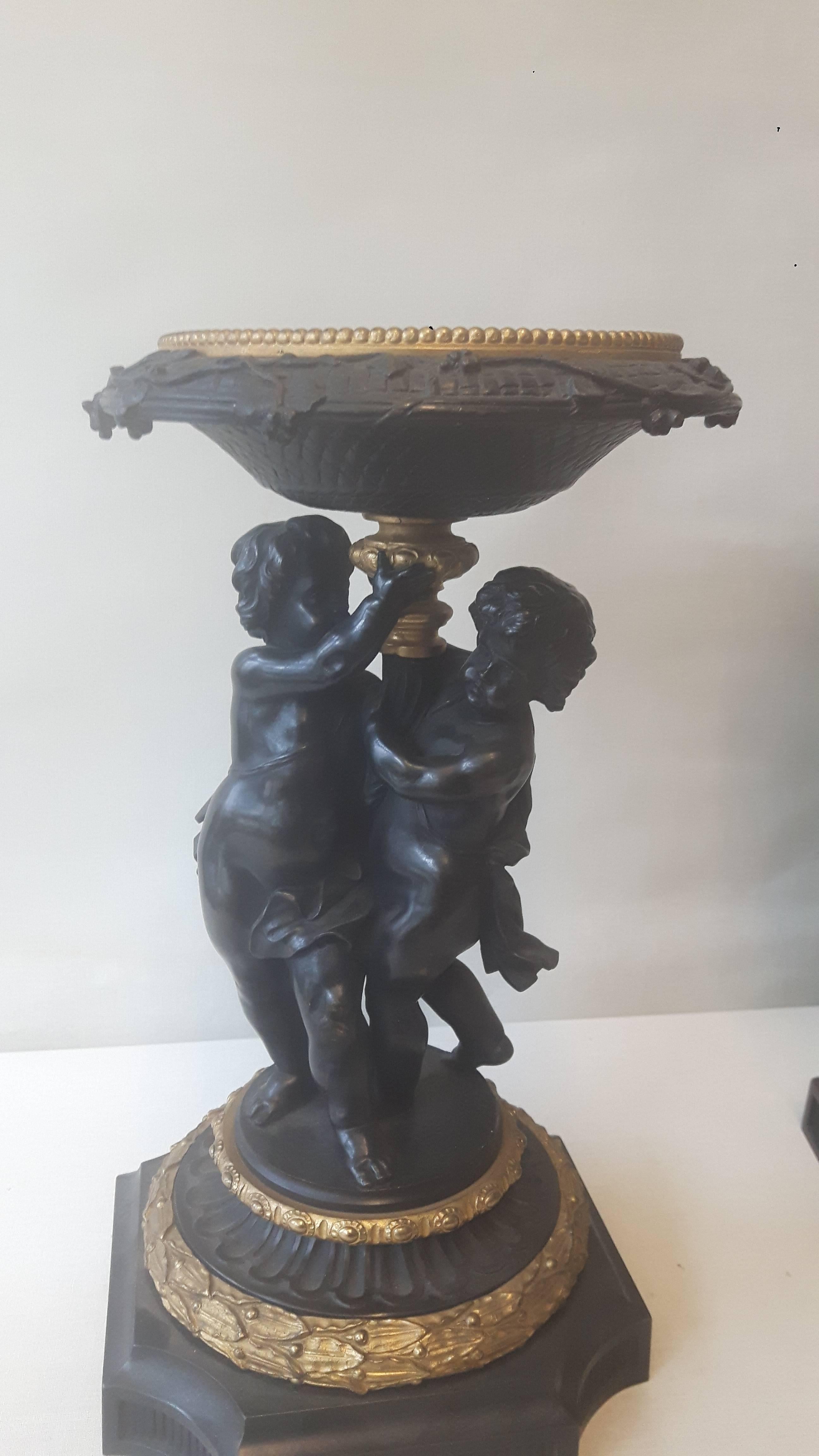 A pair of bronze and ormolu tazzas in the C17 Italian style, each tazza engraved with mythological scenes, held up by a column and two putti, in the 