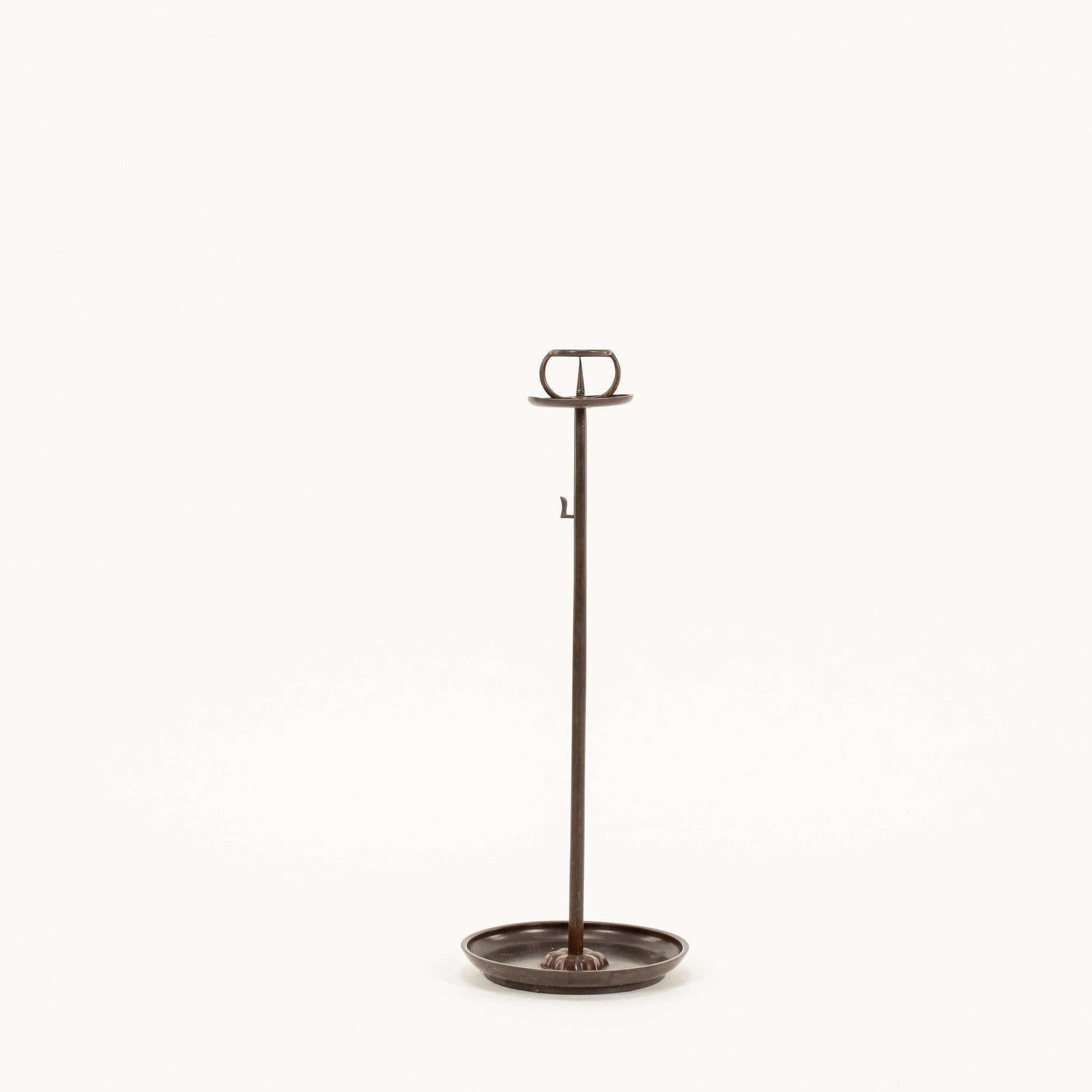 Pair of 19th Century Bronze Japanese Shokudai Candle Stands. Cast in a bronze alloy, this pair of candle stands is an example of traditional Japanese metalwork. The well-proportioned stand is quite tall, stabilized by a heavy bronze base plate. A