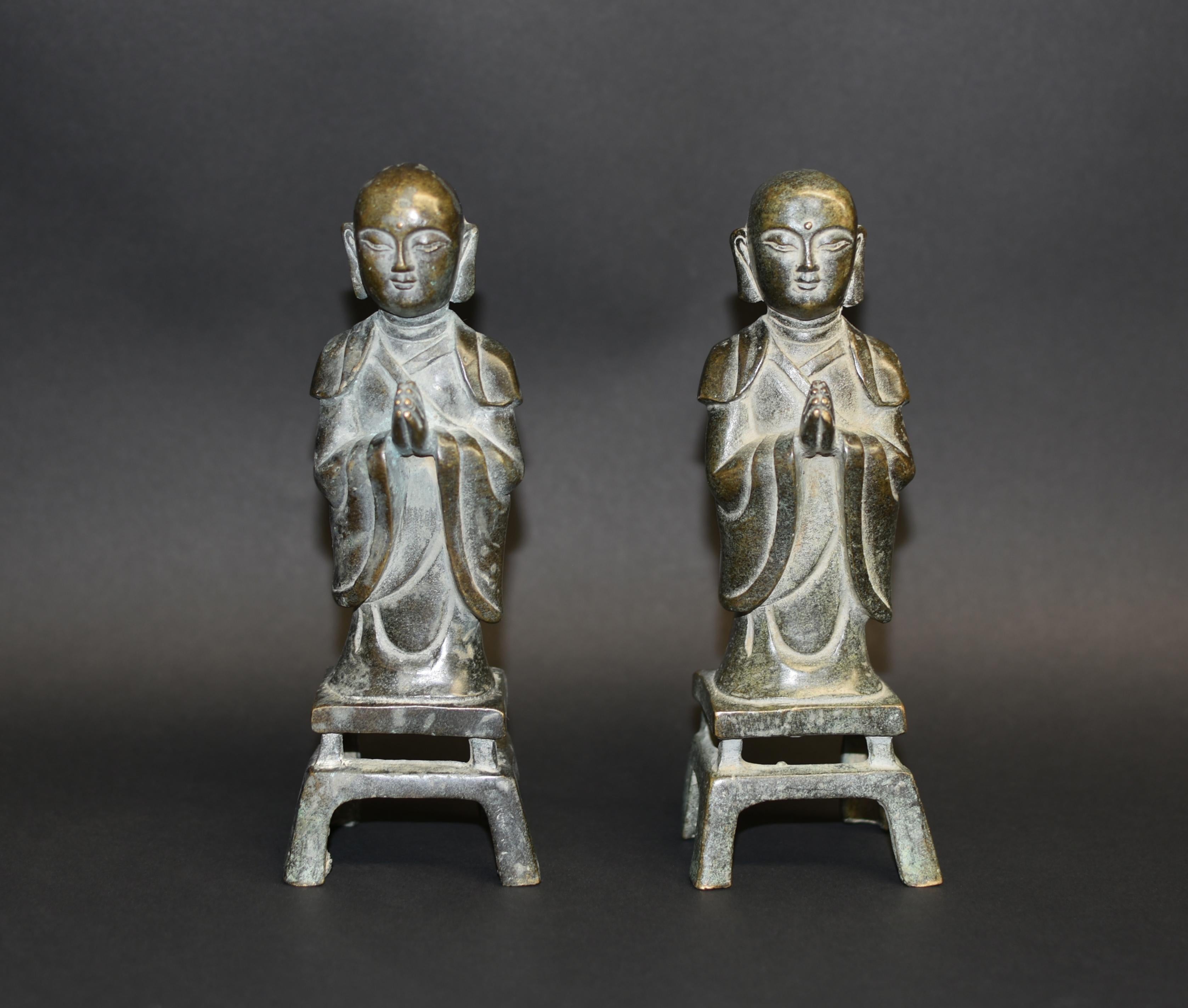 Standing atop a typical wei-style splayed four-legged plinth, the young monks rendered with a serene countenance, the round faces with large downcast eyes below arched brows, framed by long pendulous earlobes. The figures are clad in robes cascading