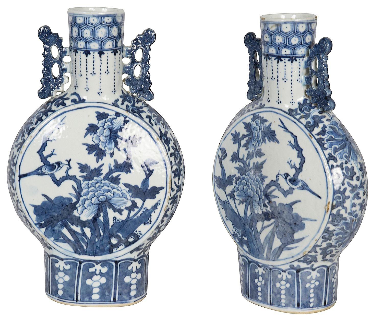 Paar chinesische blau-weiße Mondflaschen aus dem 19. Jahrhundert, jeweils mit klassischen Motiven auf den Halsbändern, durchbrochenen Henkeln auf beiden Seiten und handgemalten runden Tafeln, die exotische Blumenszenen mit einem auf einem Branch
