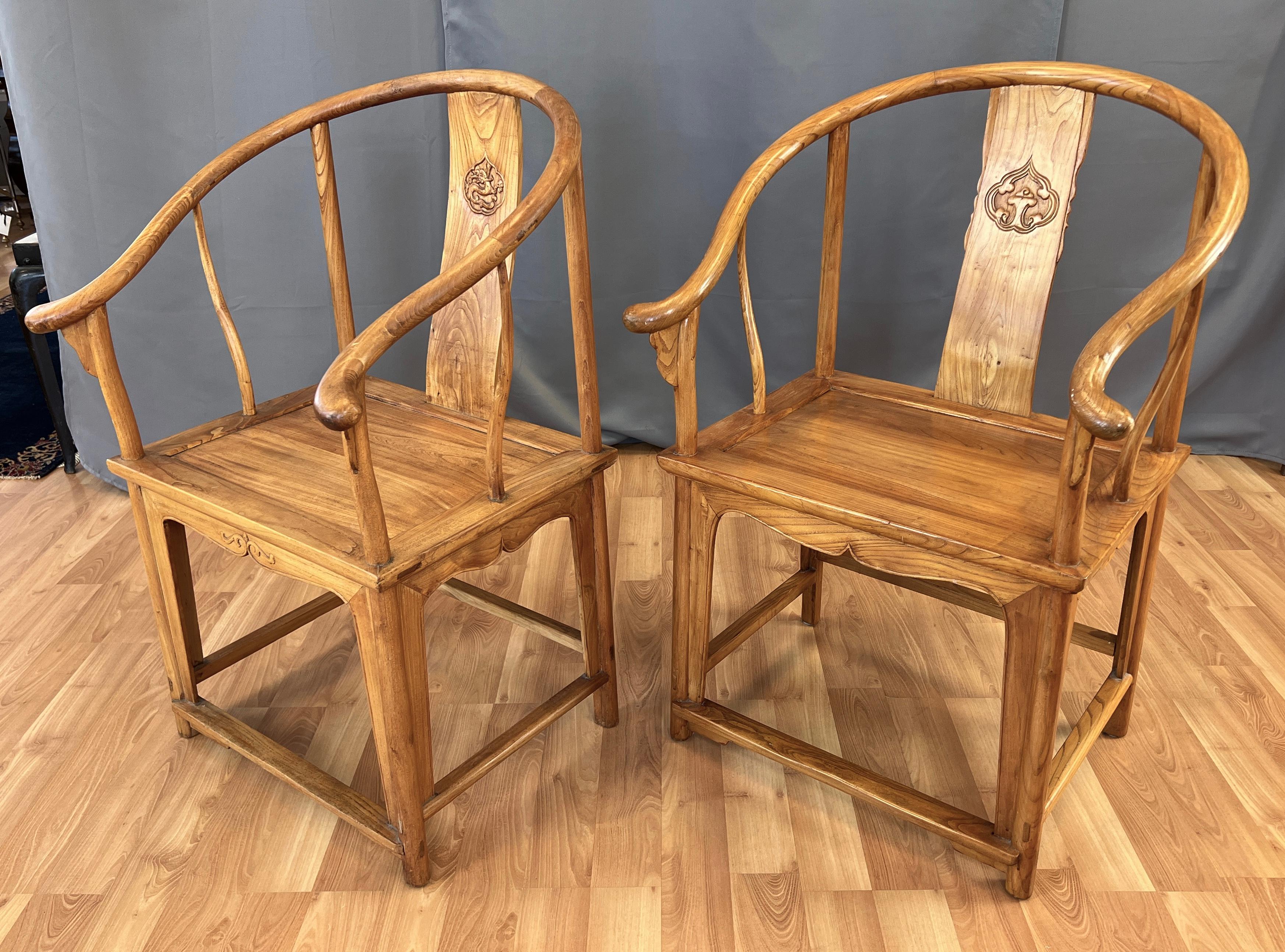 Pair 19th century Chinese Elm wood horseshoe style chairs from the Qing Dynasty era.
Horseshoe back and into arms, carved design on the center of their back panel.
Another carving on it's front skirt, and sides.
 