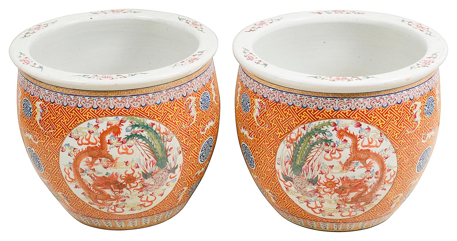 A good quality pair of late 19th century Chinese Famille Rose jardinières, each with orange ground motif decoration, inset hand painted panels depicting mythical dragons and peacocks. Measures: 48cm (19