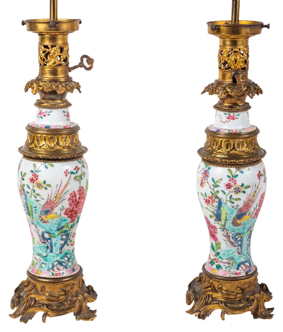 Une paire de vases / lampes en porcelaine chinoise Famille Rose du 19ème siècle de très bonne qualité. Chacune d'entre elles est ornée de magnifiques montures dorées et ornementées de style rococo. Décoration classique d'oiseaux exotiques et de