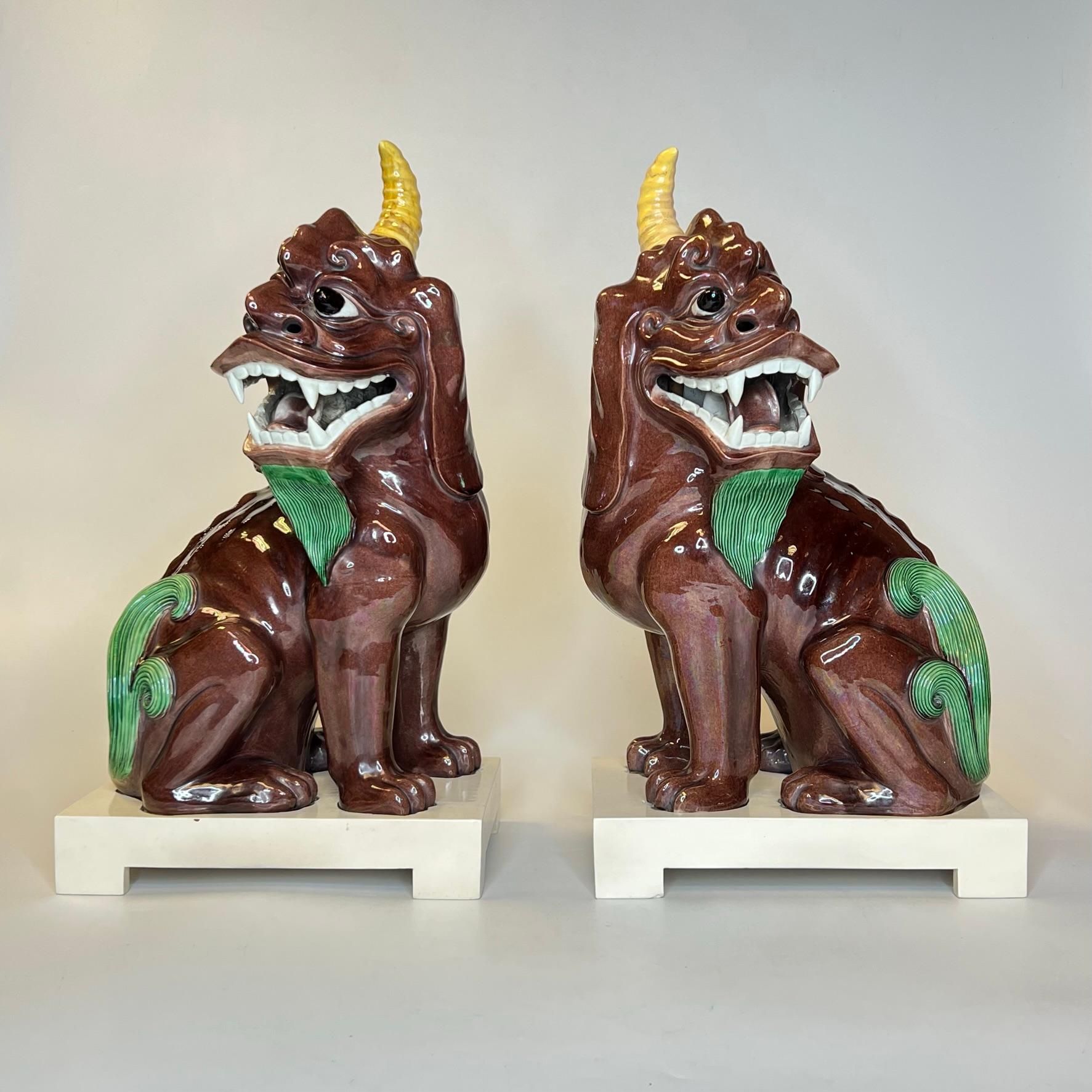 Pair of antique (early 20th century) Chinese mythological porcelain unicorns with painted wooden stands, each with Qianlong dynasty impressed marks, and circular red stamped export marks.  Each in excellent condition.
