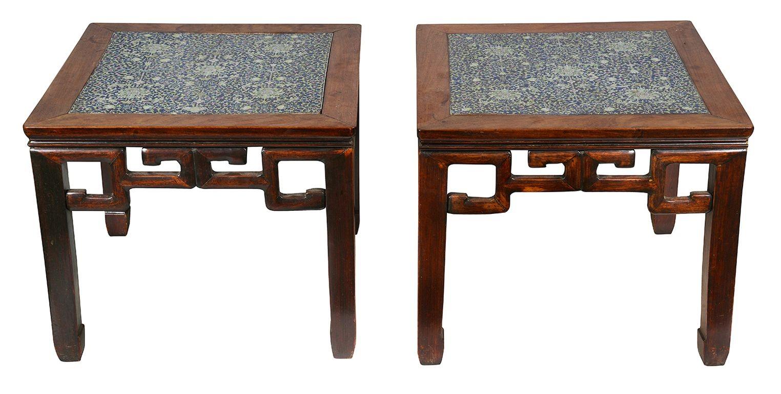 This exquisite pair of 19th-century Chinese hardwood stands is a stunning example of craftsmanship and artistry. Each stand features an inset Famille Rose porcelain panel, renowned for its vibrant colors and intricate floral designs. The hardwood