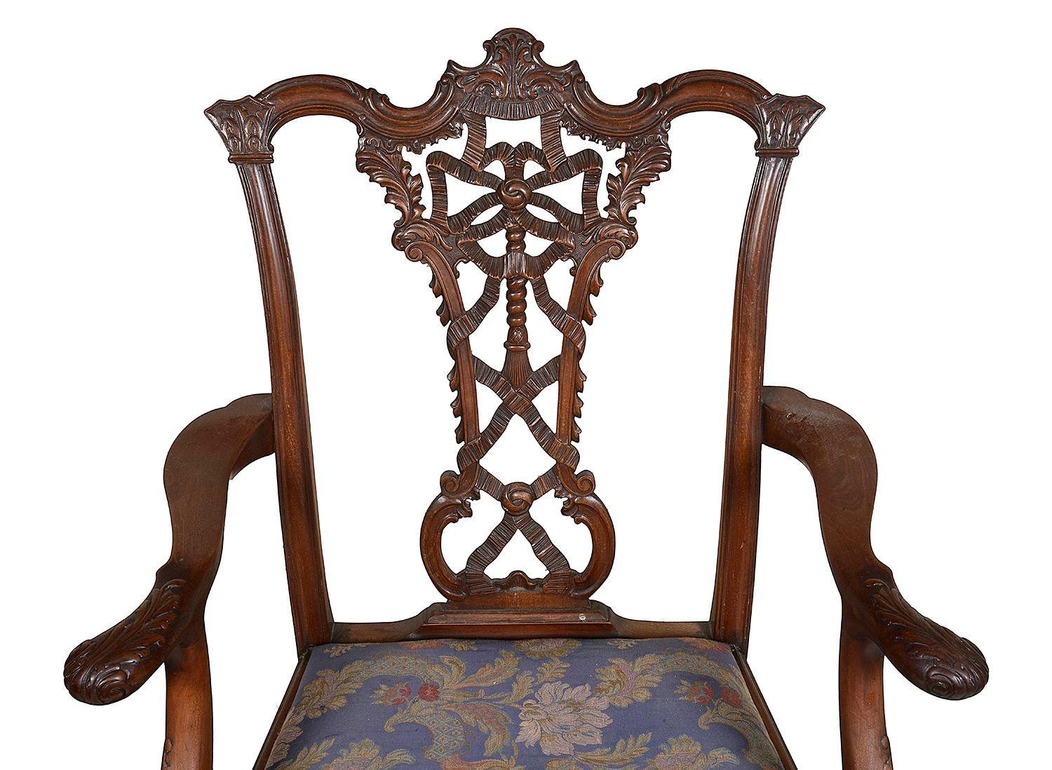 Une paire de fauteuils de style Chippendale en acajou anglais du 19ème siècle, chacun avec un magnifique dossier sculpté à la main, des sièges rembourrés et reposant sur des pieds cabriole, terminés par des pieds en forme de boule et de