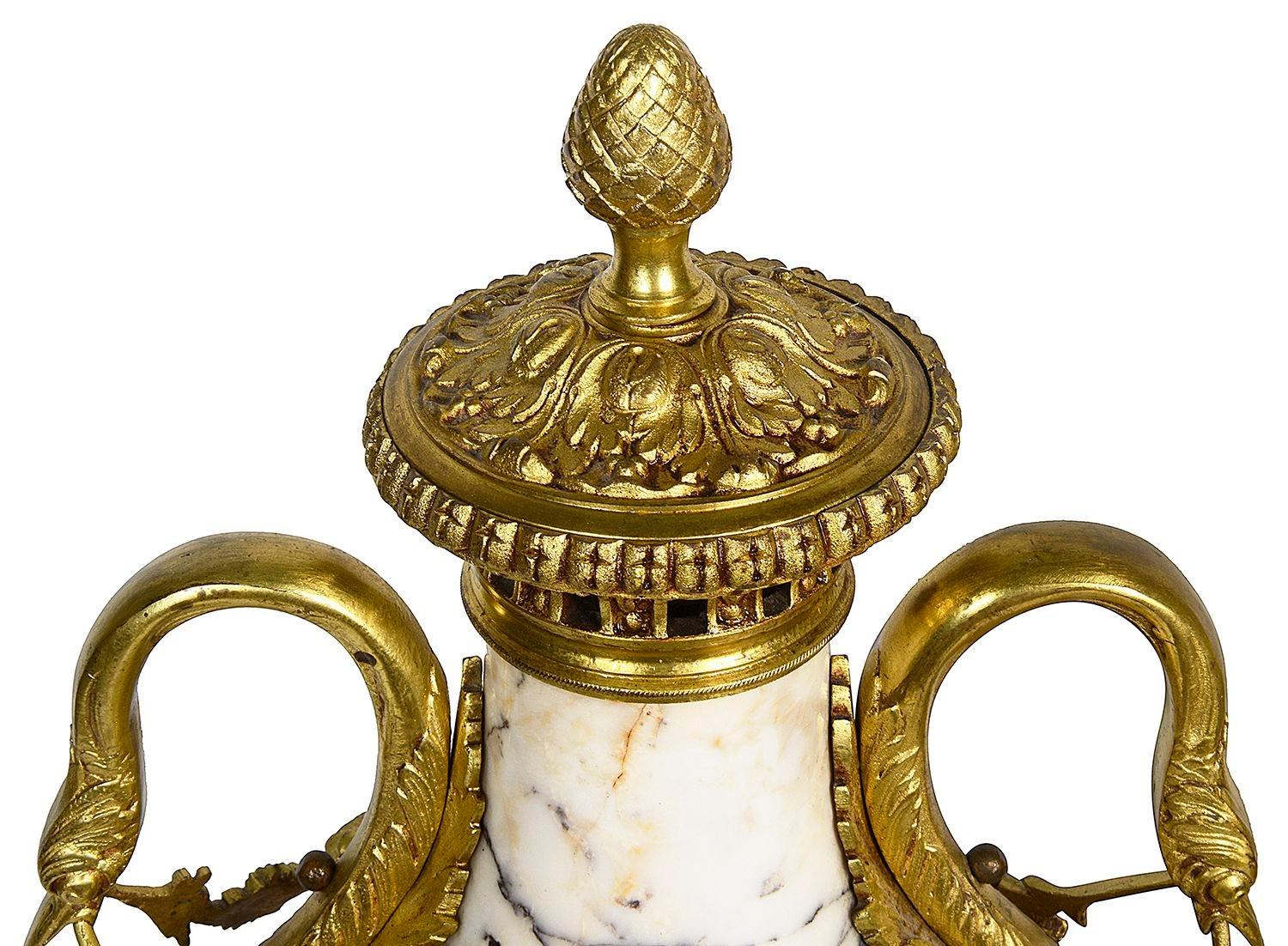 Pair of Classical 19th Century French Louis XVI style marble and gilded ormolu lidded urns. Each with swan head handles and floral swag decoration, raised on plinth bases.

Batch 75 Giooo5/23 CNKZ