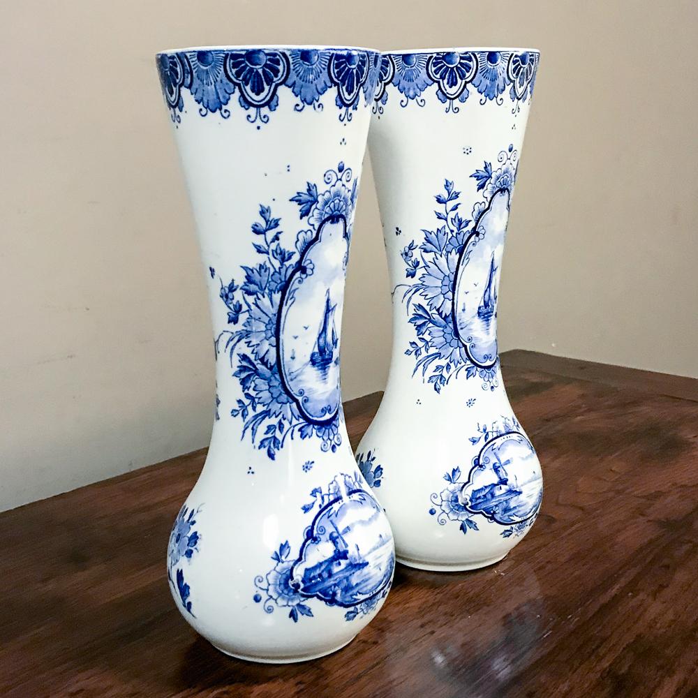 Pair 19th century Dutch blue and white vases features stunning cobalt blue hand painted atop white porcelain for lovely contrast, a technique developed in China centuries ago, then copied by European makers in subsequent years. This example depicts