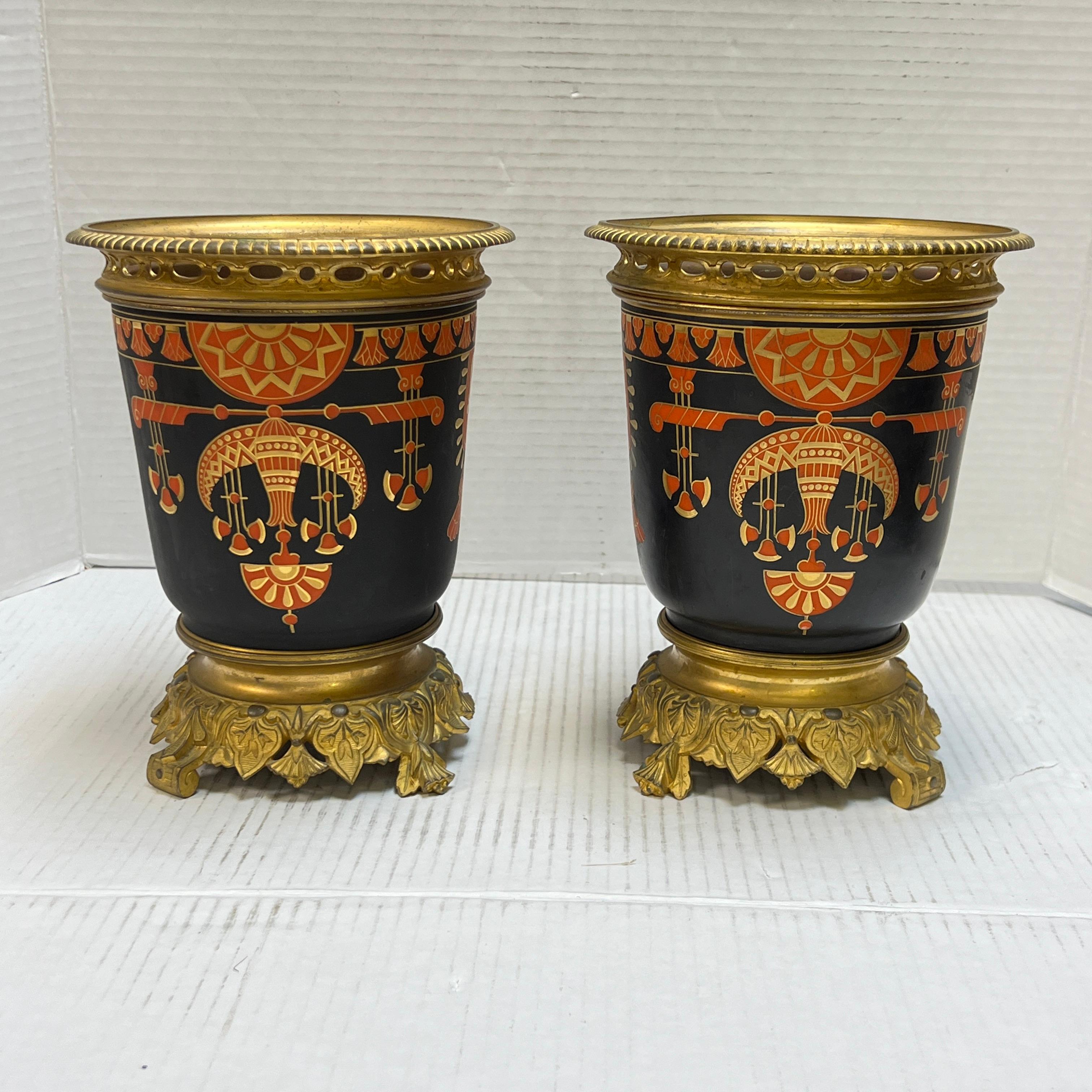 Coppia di vasi o cachepot (fioriere) in bronzo dorato francese del XIX secolo in stile Impero francese, circa 1880, che si distinguono per i disegni egiziani dipinti a freddo in rosso, oro e nero.  

