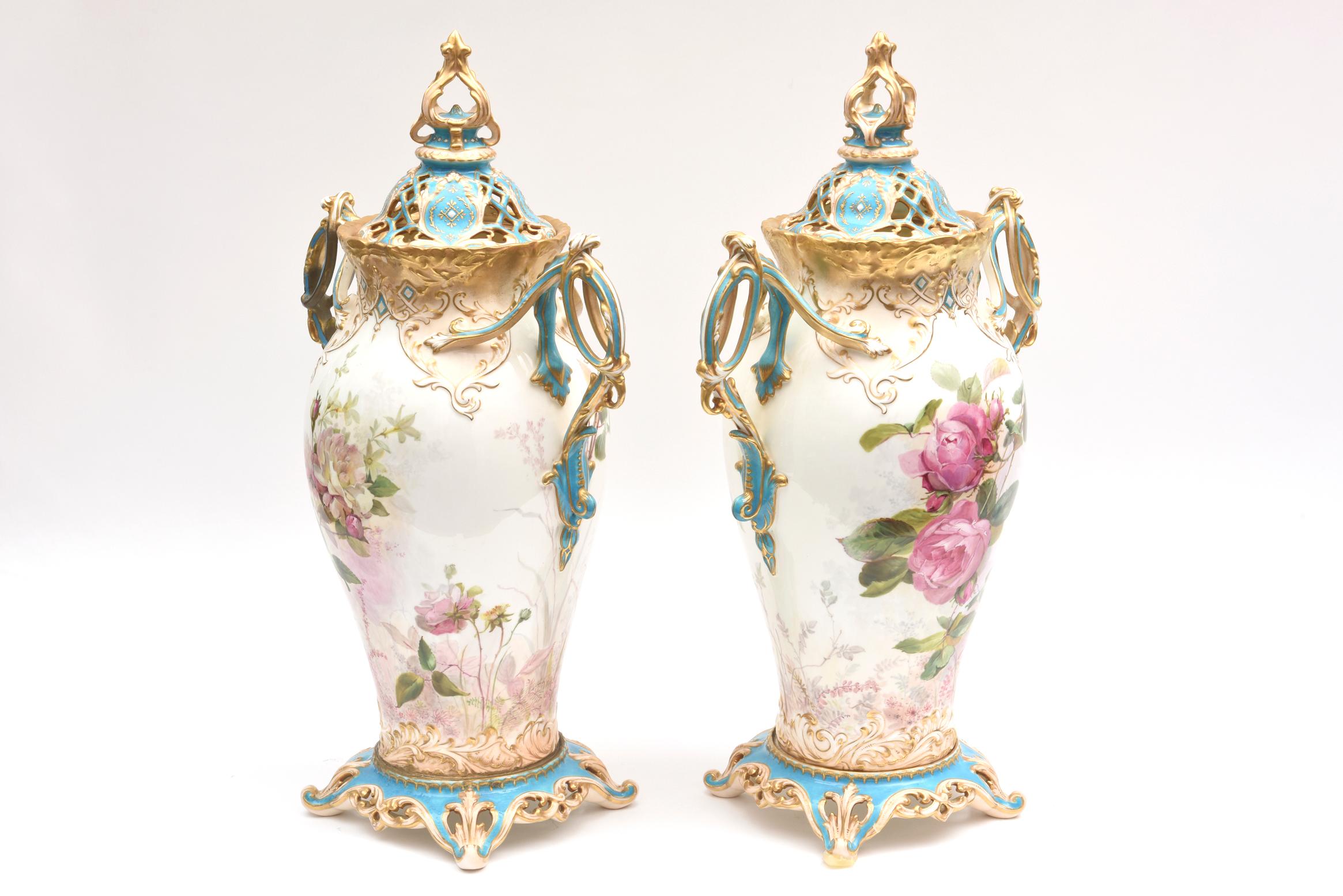 An outstanding and hard to find pair of antique porcelain vases with their original lids. Finely painted and Artist-signed roses and flora fauna surround the detailed body of the vases. Bright and colorful turquoise hand enameling accent throughout