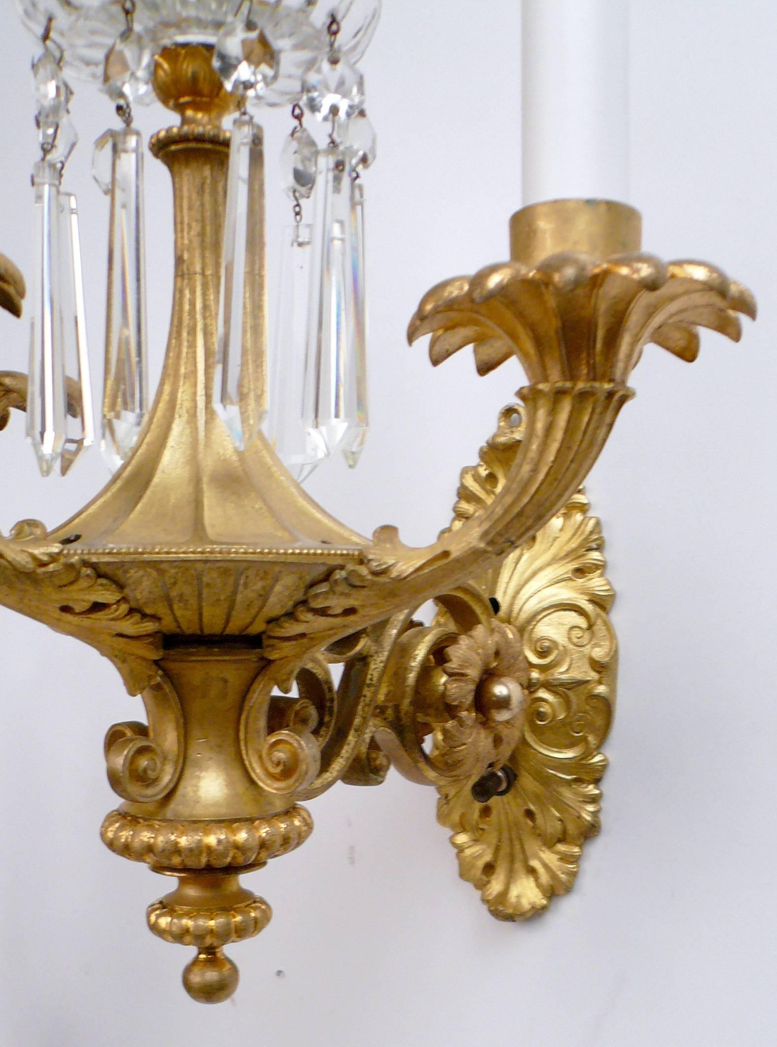 This handsome pair of William IV three light sconces feature classical motifs including urn and acanthus leaf designs, and cut crystal obelisks.