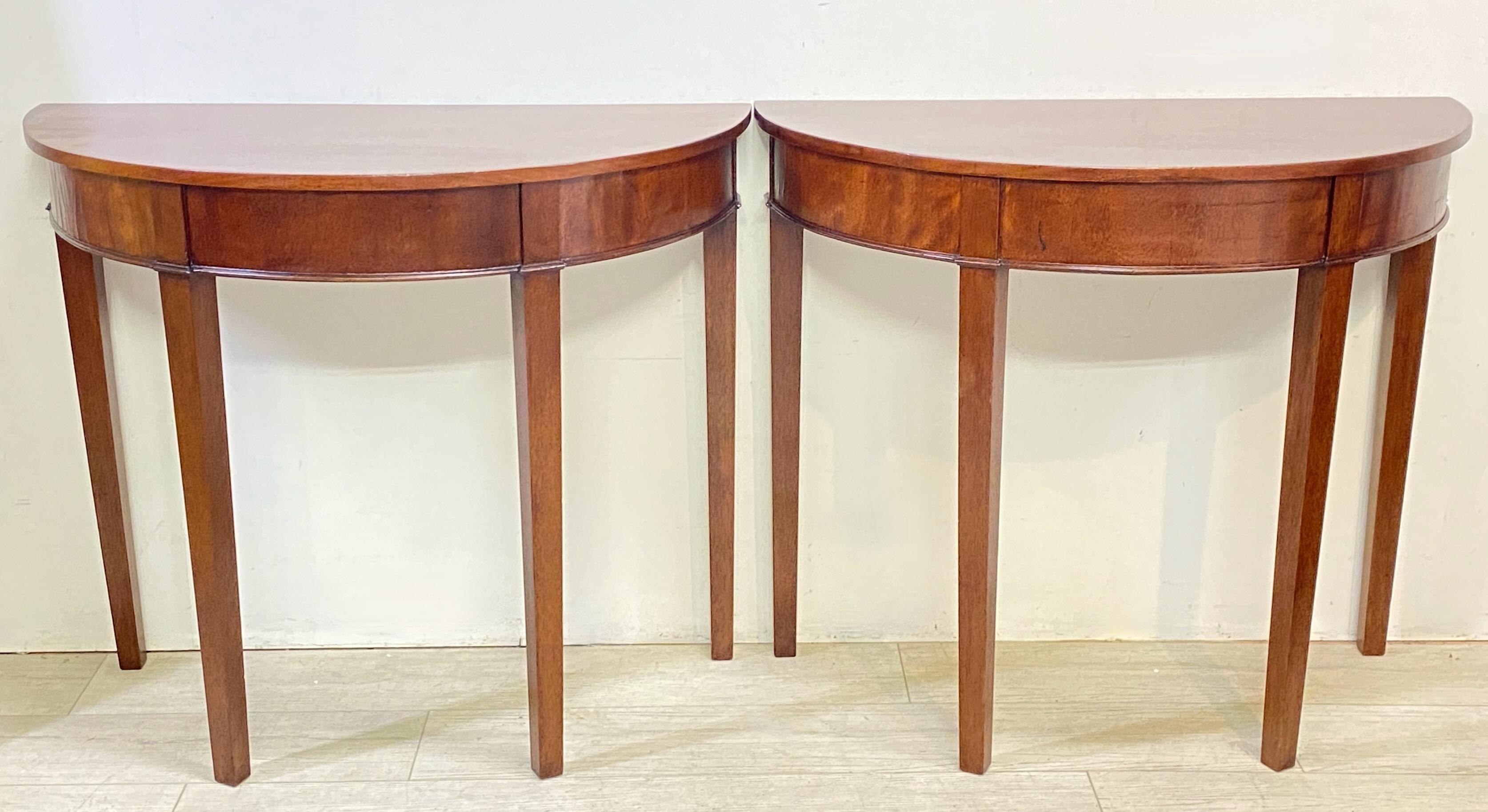 A classic pair of Georgian period mahogany Demi Lune console tables that fit together to make a circular center table.
Originally had center leaf (now missing).
England, early 19th century.
In excellent antique condition.
  