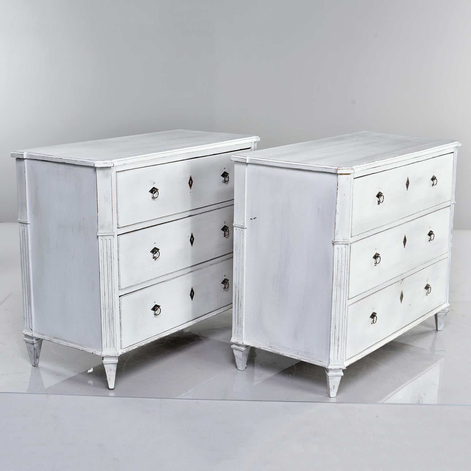 Found in England, this pair of three-drawer pine chests dates from the 1880s. Reeded details on side supports, brass ring pull hardware and new antique white matte paint. Unknown maker. Sold and priced as a pair.