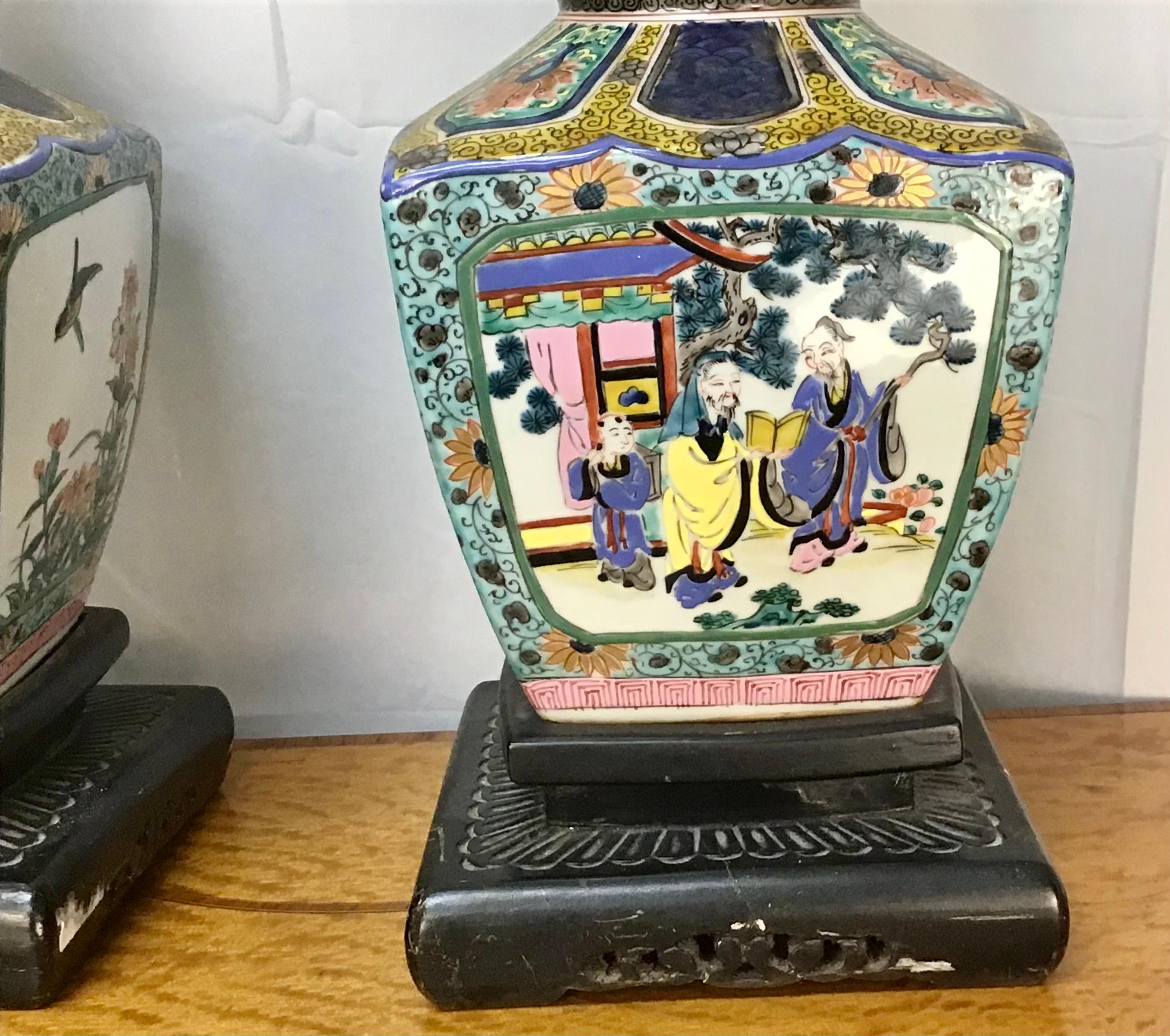 Rare pair decorated with court figures engaged in leisurely pursuits, on carved wood bases. Bright vivid and colorfully hand painted motif. Please note shade is not included.