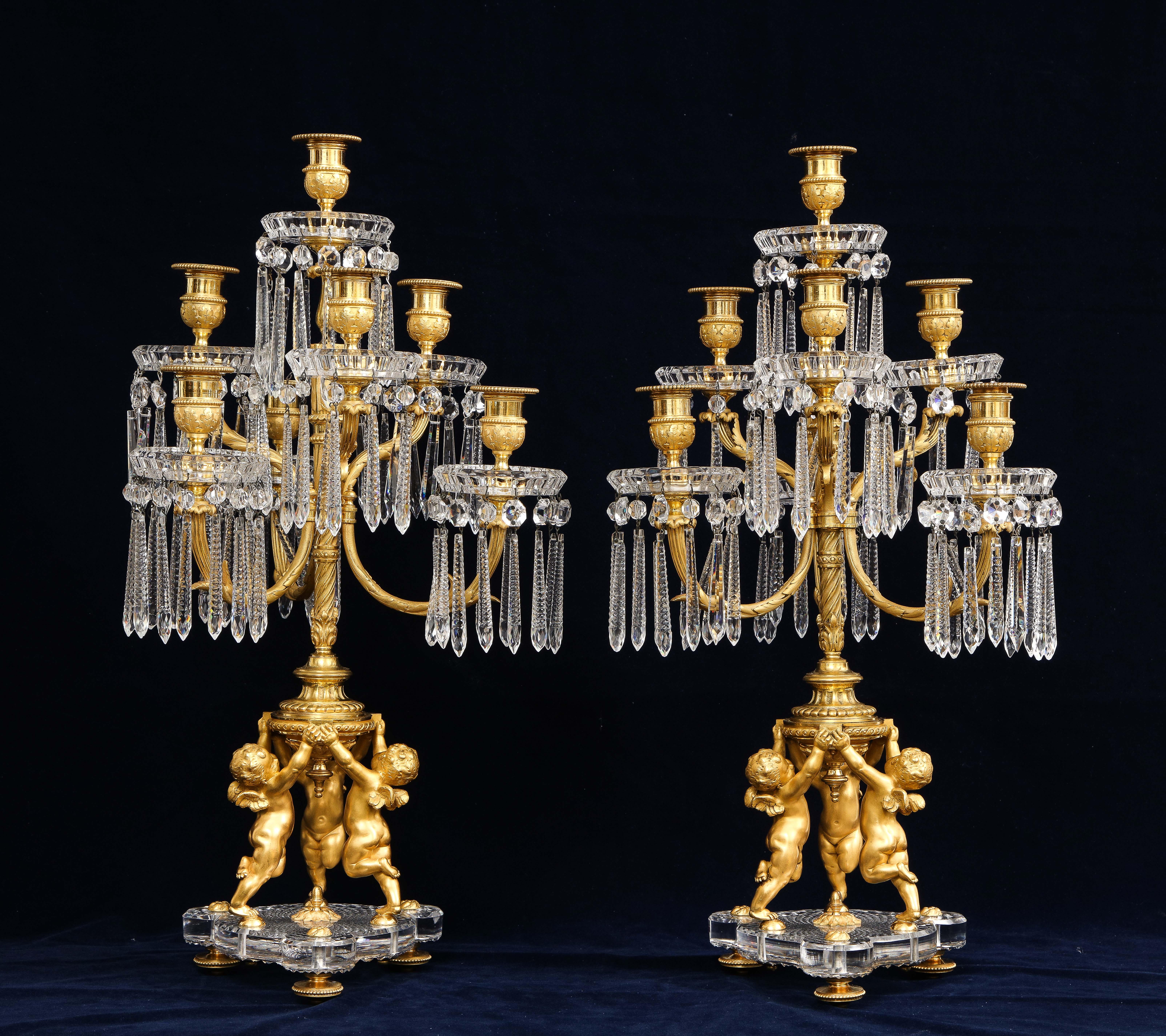 Une grande et magnifique paire de candélabres de style Louis XVI à sept bras en bronze doré et cristal, signée Baccarat. Chaque candélabre est doté de sept chandeliers en bronze doré qui sont ornés de décorations en feuilles d'acanthe mates et