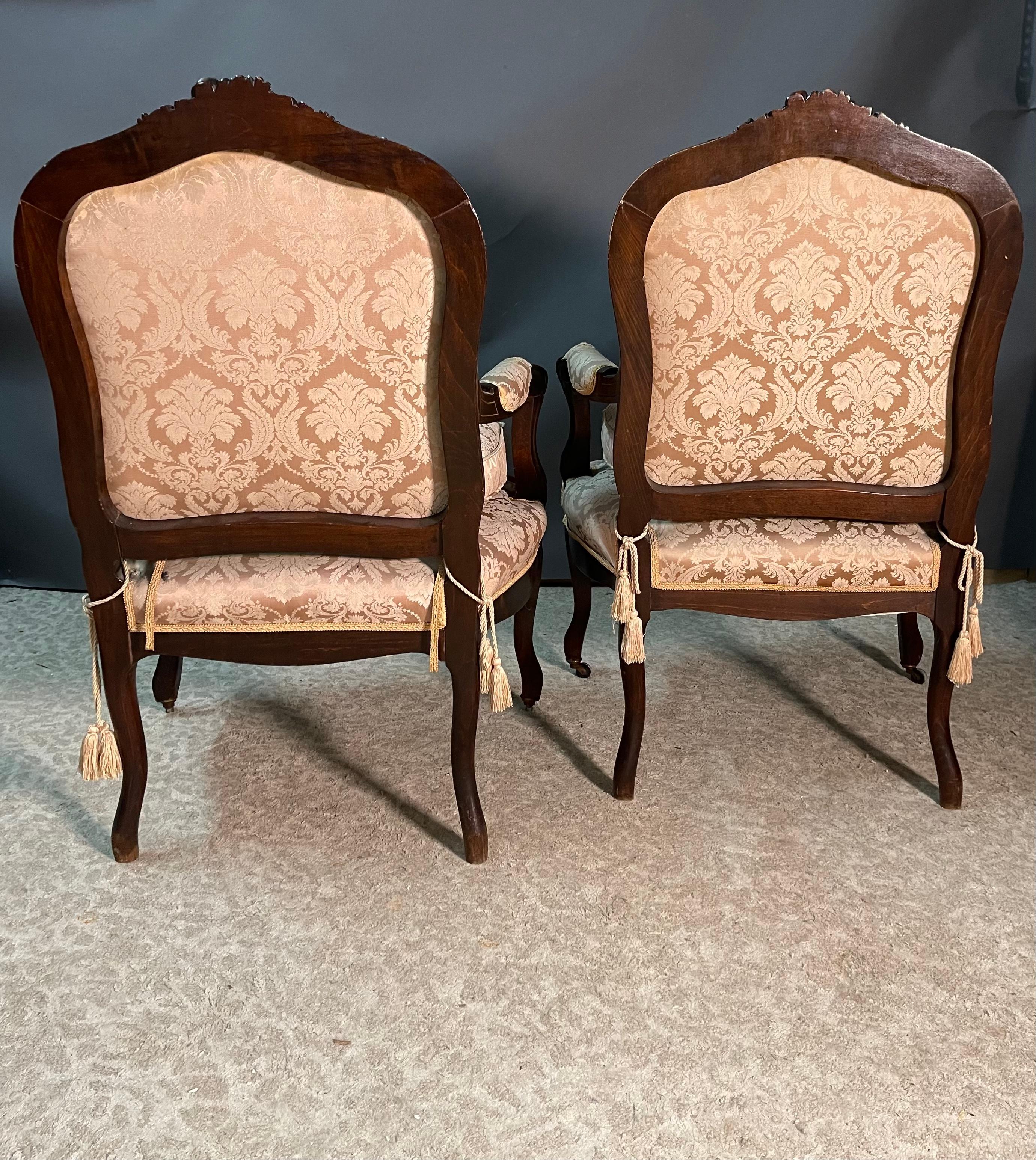 Esta hermosa pareja de sillones del siglo XIX, de estilo francés Luis XV, presenta un respaldo cómodamente curvado y envolvente y un cojín de asiento acolchado, suelto pero entallado. 
Tapizadas en tela de Damasco crema, estas sillas, con sus