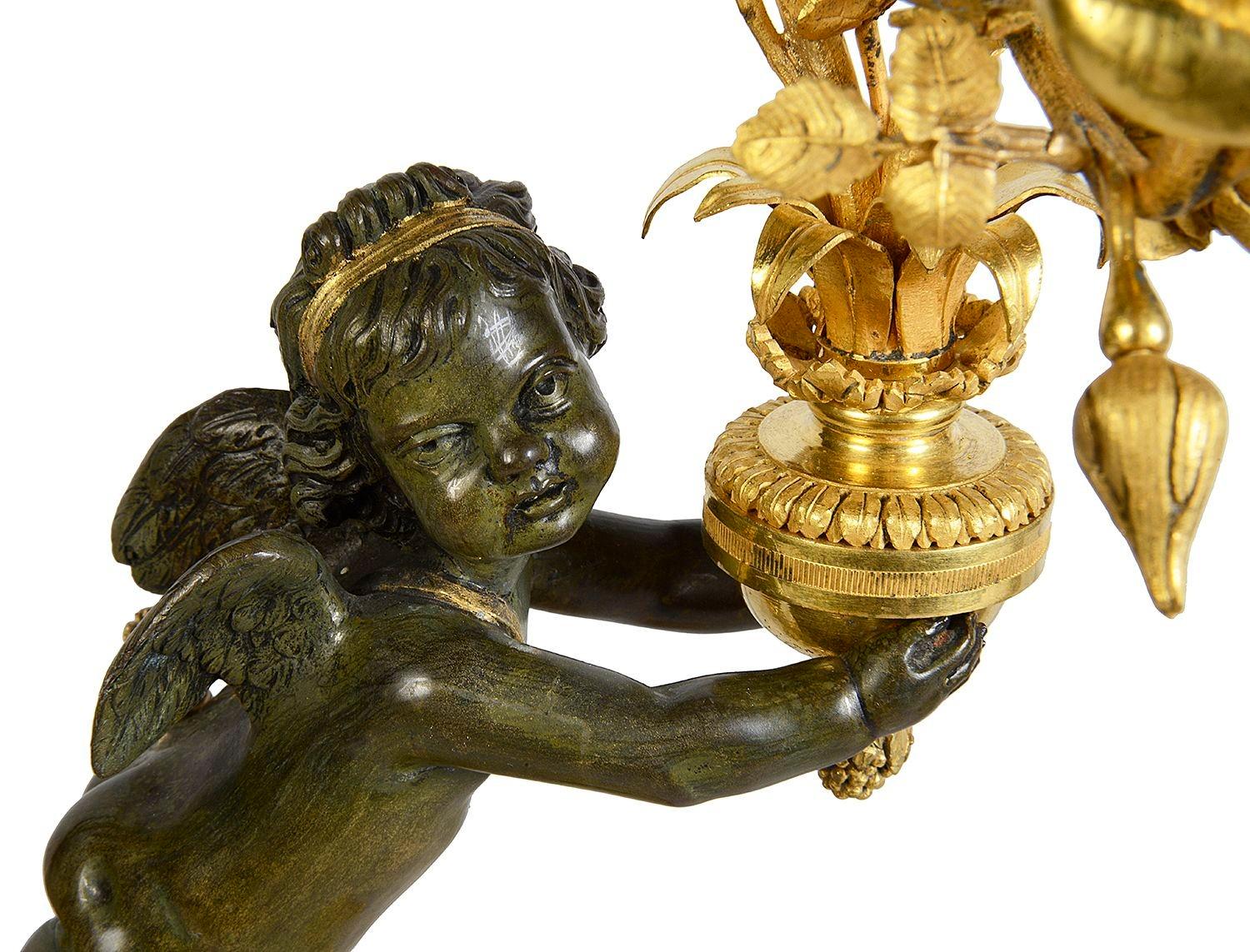 Coppia di candelabri a tre rami in ormolu dorato, bronzo patinato e marmo bianco, di buona qualità, risalenti al XIX secolo. Ognuno di essi presenta un giocoso cherubino che regge le luci, montato su basamenti di marmo bianco con montature a