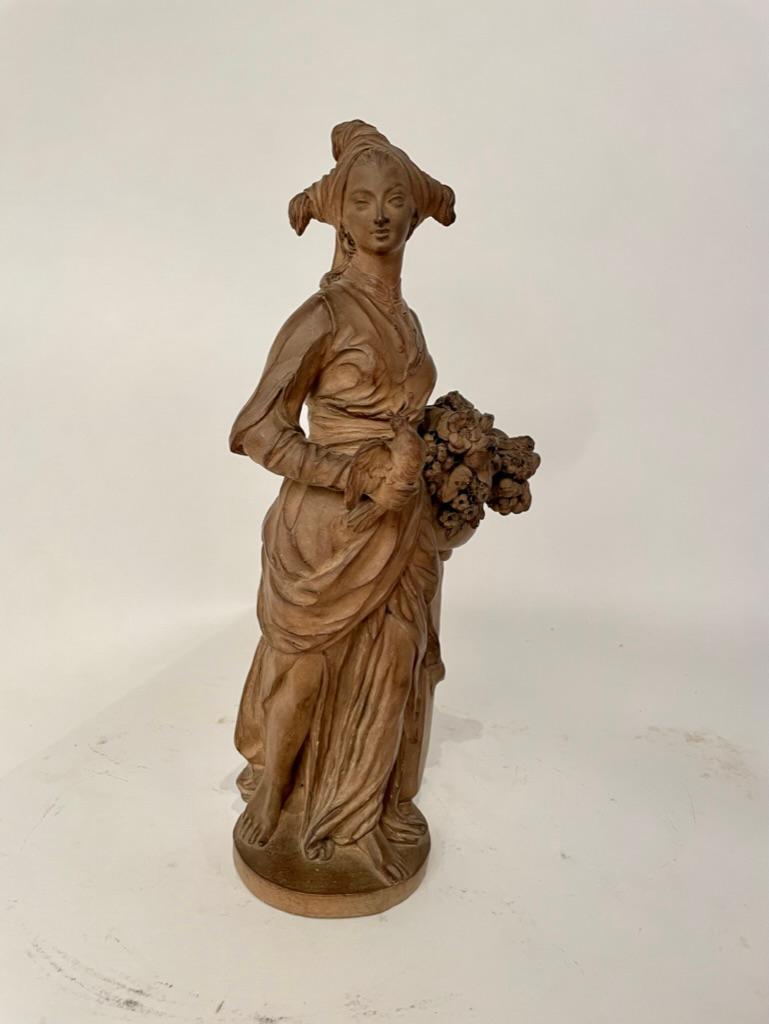 Pair of French Rococo style terracotta figures of bird sellers, both female, one holding a dove and a birdcage the other a dove and bouquet of flowers. Both figures are beautifully modeled, both very interesting head wear and clothing in the