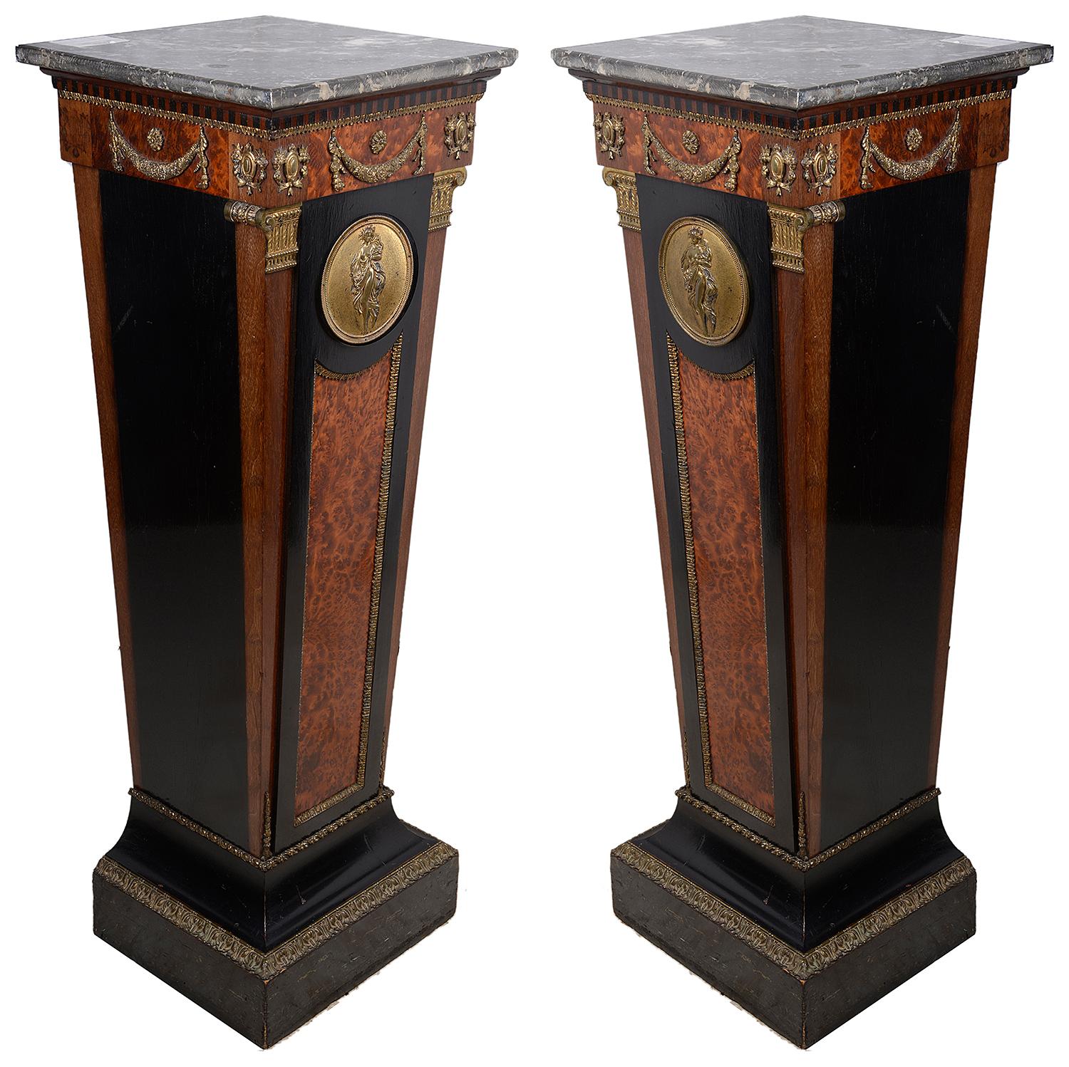 A good quality pair of 19th century French marble topped pedestals, each with classical gilded ormolu mounts of swags and columns, the circular plaques to the centre, depicting semi clad maidens. Ebonized and burr wood veneers.

 