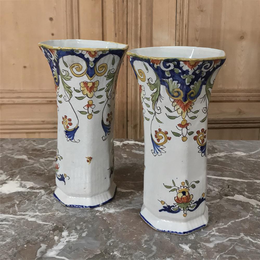 Hand painted pair 19th century French colorful faience vases were crafted in the storied city of Rouen located in the fertile fields of Normandy, France. This pair of tall antique vases features rich traditional country French colors with floral