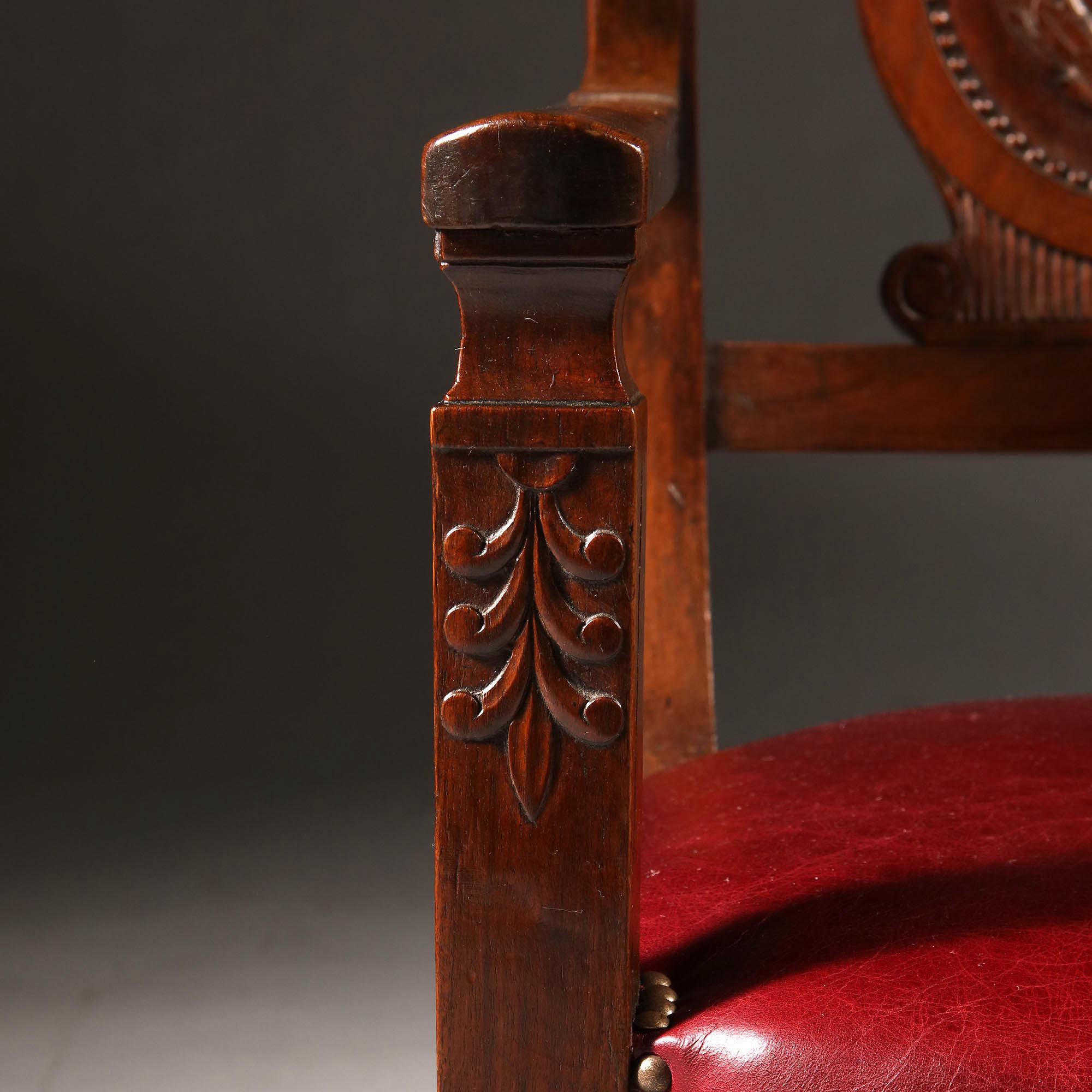 A pair of 19th century Empire mahogany fauteuils, with unusual back splats carved with a roundel of laurel leaves to the centre, layered on top of a Greek lyre form, the seats upholstered with red Morocco leather.