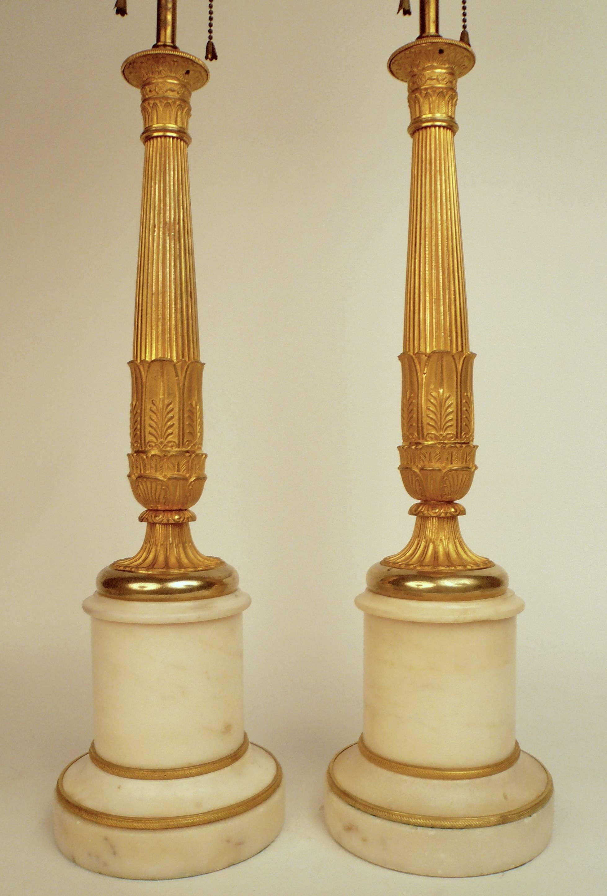 This fine pair of bronze and marble lamps feature neoclassical motifs including acanthus leaves and tapering reeded columns.