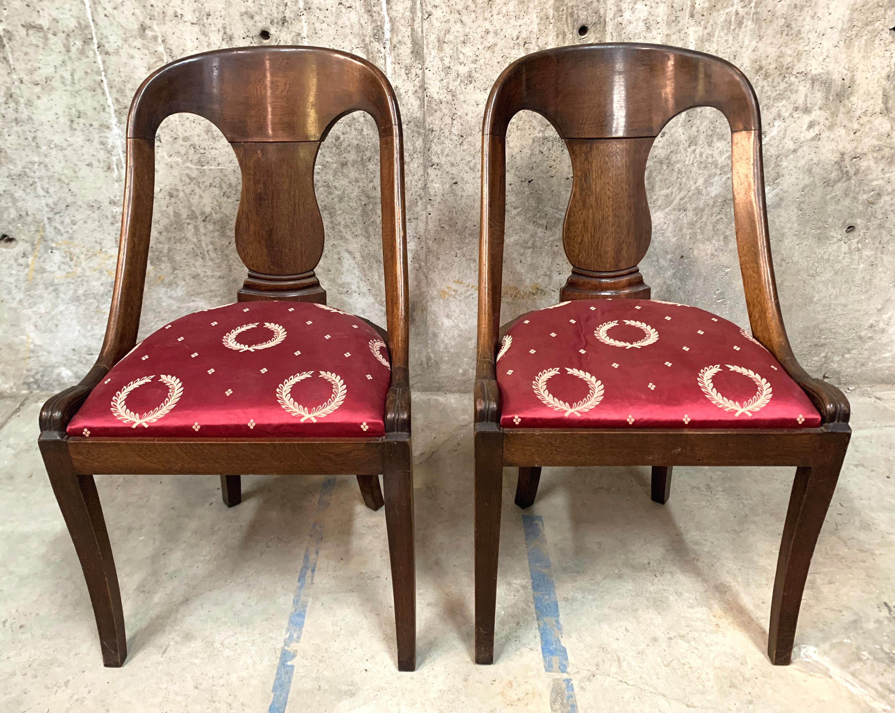 Extraordinary pair of French Empire style mahogany chairs featuring a tub or gondola form frame. Minimally decorated having a curved back, vasiform back splat surmounted by a curved crest rail. Gracefully curved back supports conjoined to a red silk