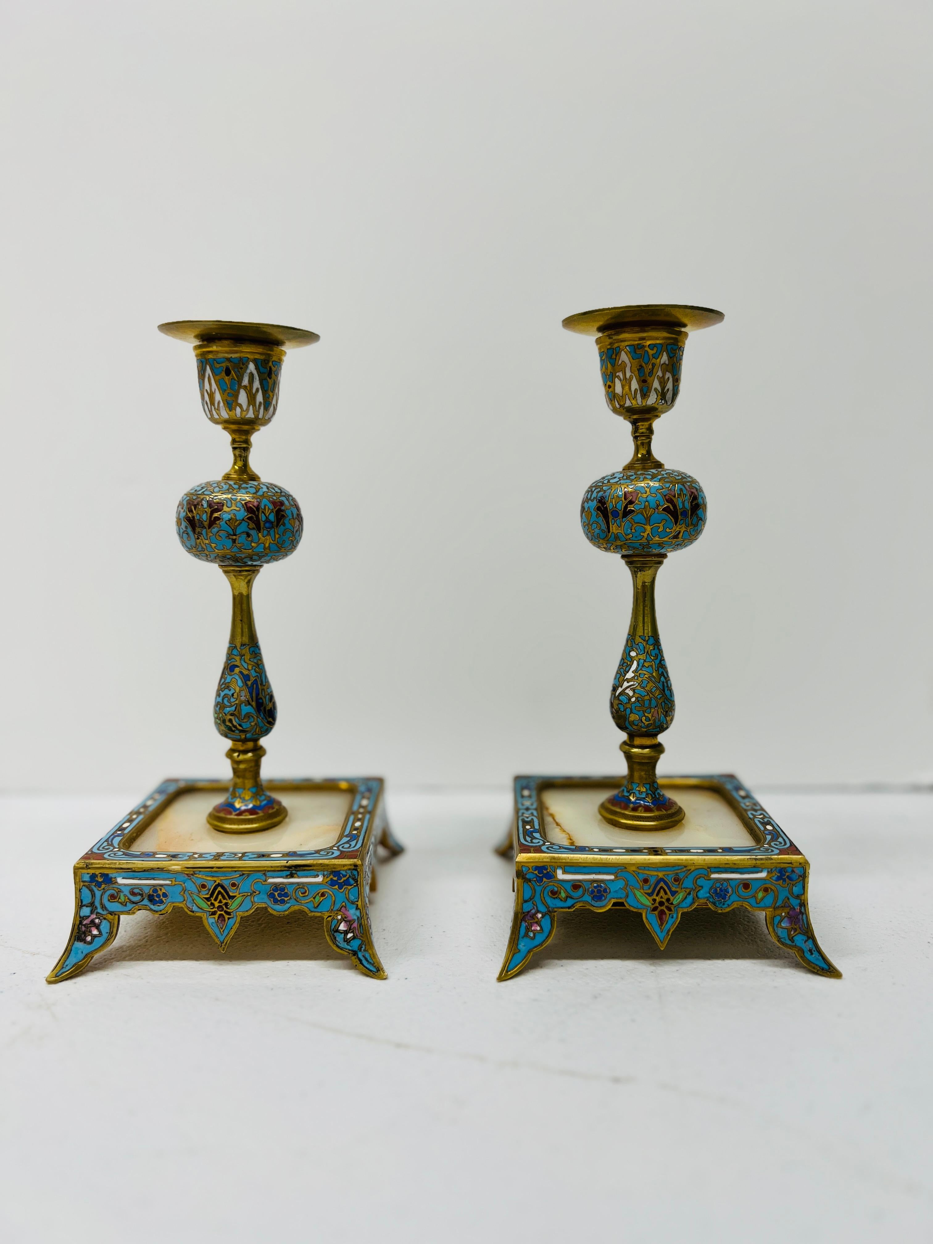 Questa squisita coppia di candelieri francesi del XIX secolo combina i lussuosi materiali del bronzo dorato, dello smalto cloisonné e dell'onice per creare uno straordinario spettacolo di opulenza e maestria. I candelieri sono caratterizzati da