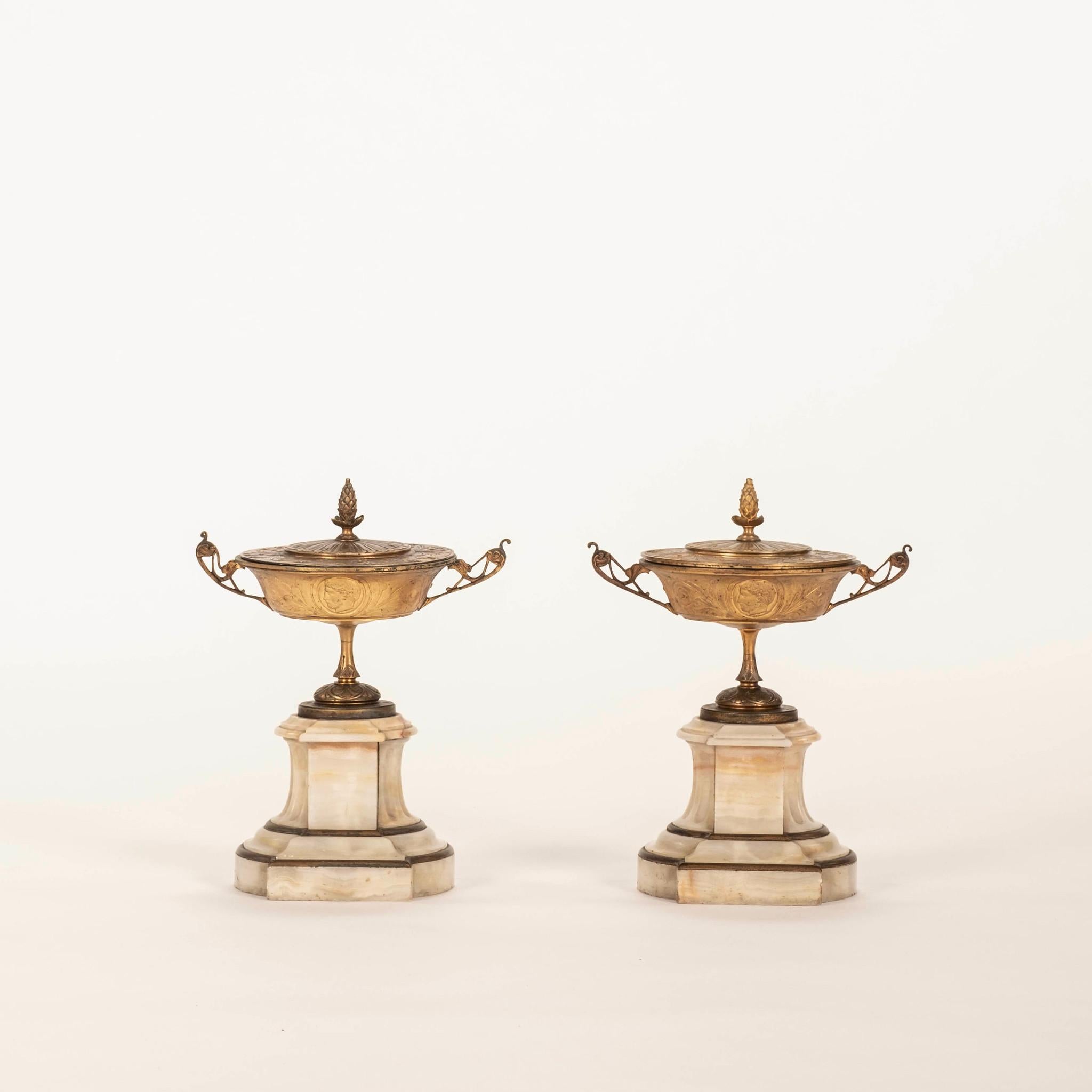 Paire de garnitures néoclassiques françaises du XIXe siècle, comprenant des urnes à couvercle en bronze doré sur des bases en marbre.