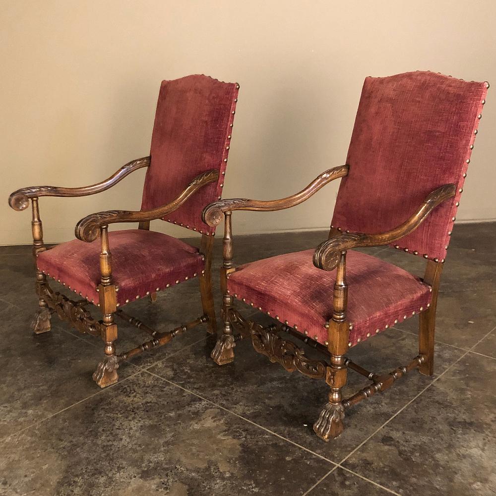 Pair 19th century French Louis XIII Fauteuils, armchairs were sculpted from solid fruitwood, and feature gracefully scrolled armrests coupled with high, arched seatbacks and generous seats resulting in uncommon comfort. The lower apron was