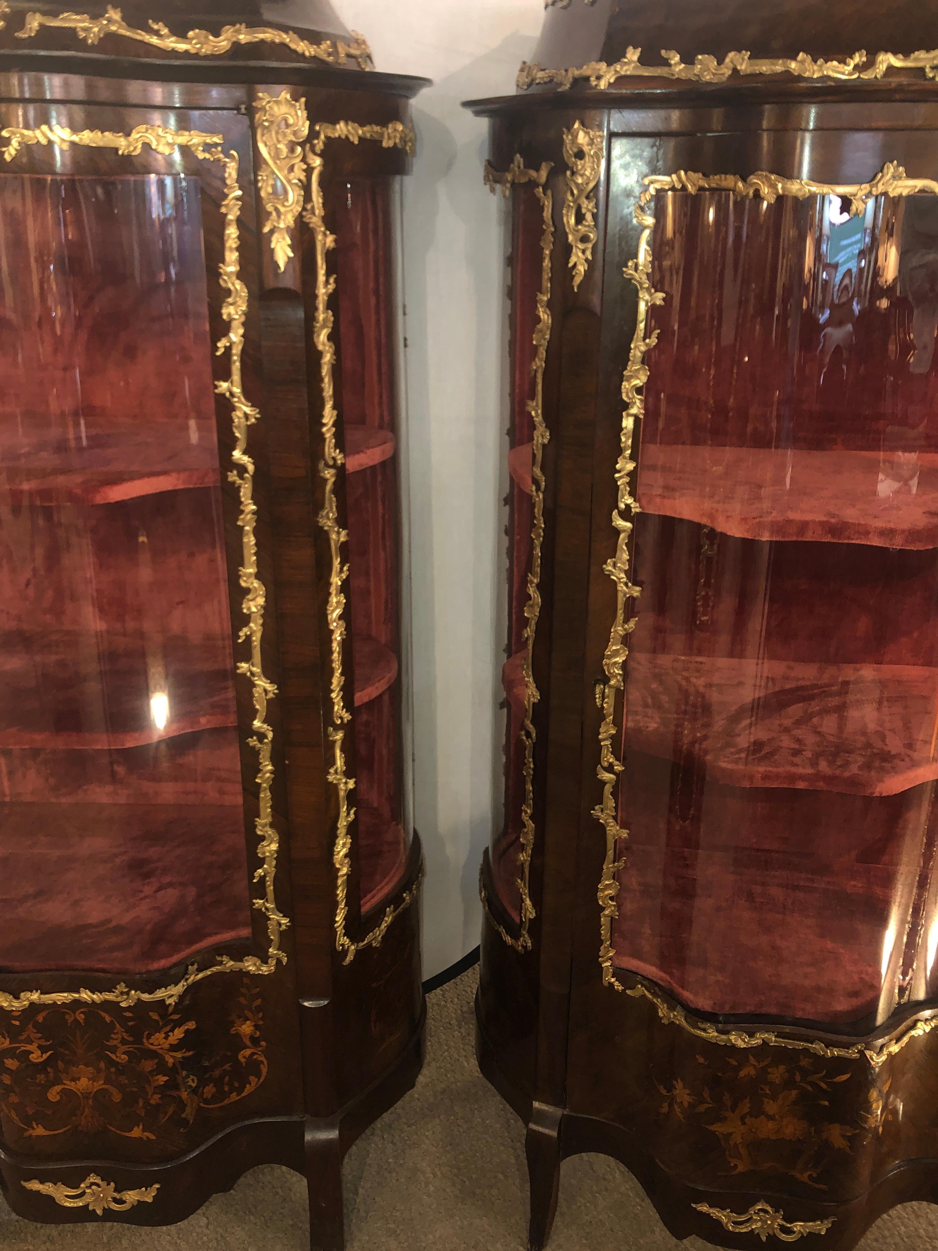 Pair of compatible 19th or early 20th century French Louis XV style bronze mounted inlaid vitrines or curio cabinets. Each having been fully refinished with new recovered velour interiors. The center double serpentine glass front doors leading to