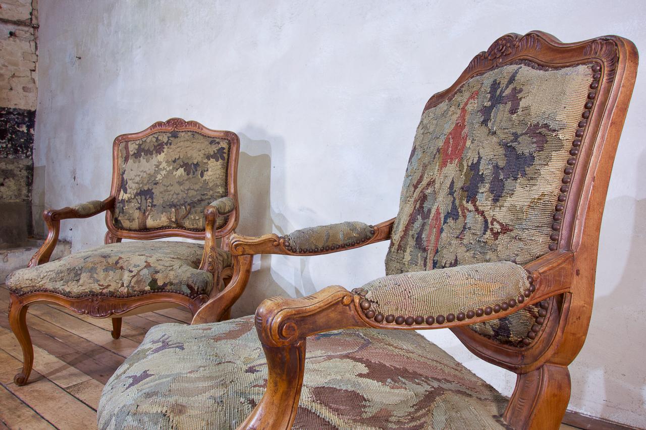 A pair of French Louis XV Fauteuils open armchairs, upholstered Aubusson tapestry.

Displaying cartouche shaped backs, demonstrating foliate scroll cresting with foliate scroll arm supports and serpentine padded seats. Upholstered in an 18th