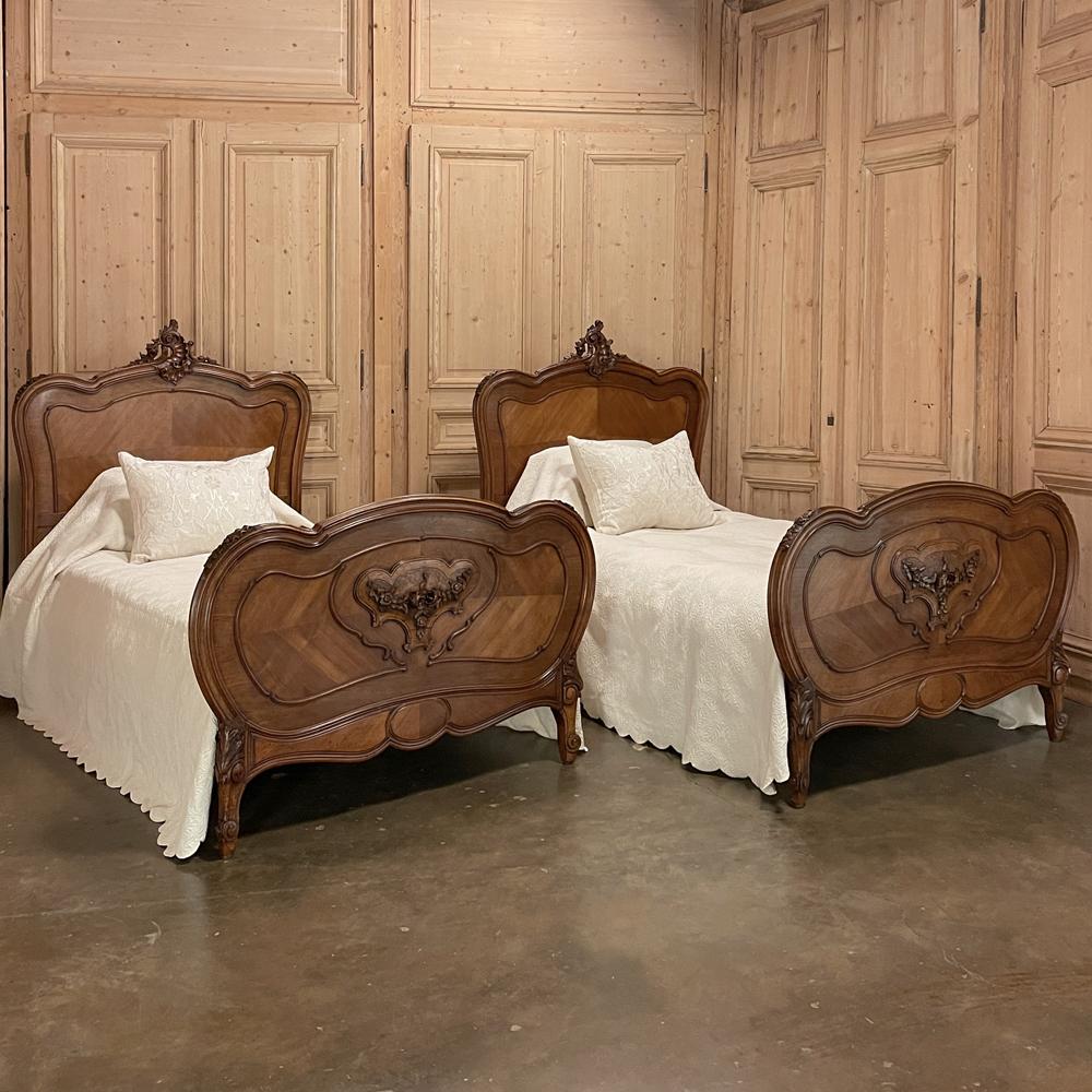 Pair 19th century French Louis XV walnut twin beds represent the essence of the style, created in sumptuous French walnut with elegance and grace. The triple arched headboard is crowned with an elaborate asymmetrical shell cartouche, with bold