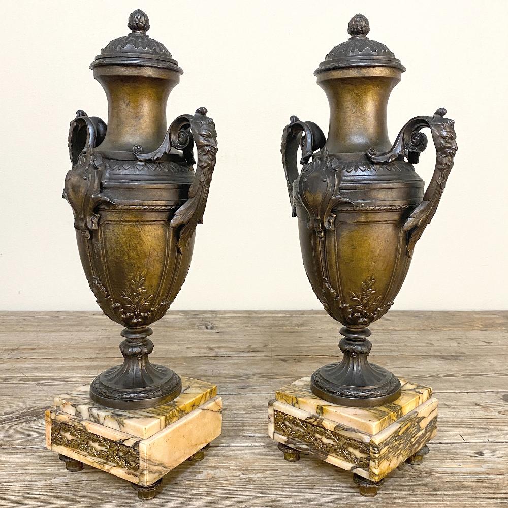 La coppia di orci da camino francesi Luigi XVI del XIX secolo su base di marmo era destinata alla sola decorazione e presenta am designs classici ispirati alle antiche anfore greche e agli abbellimenti architettonici romanici.  Fuso in spelta,