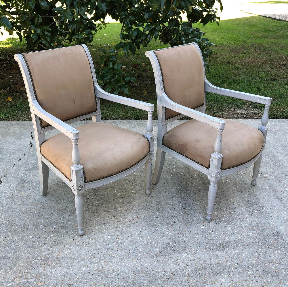 Pair 19th century French Louis XVI painted armchairs are an excellent example of the neoclassical style, and feature carved accents enhanced by the patinaed painted finish. Upholstery is serviceable yet easily replaced with your coordinating