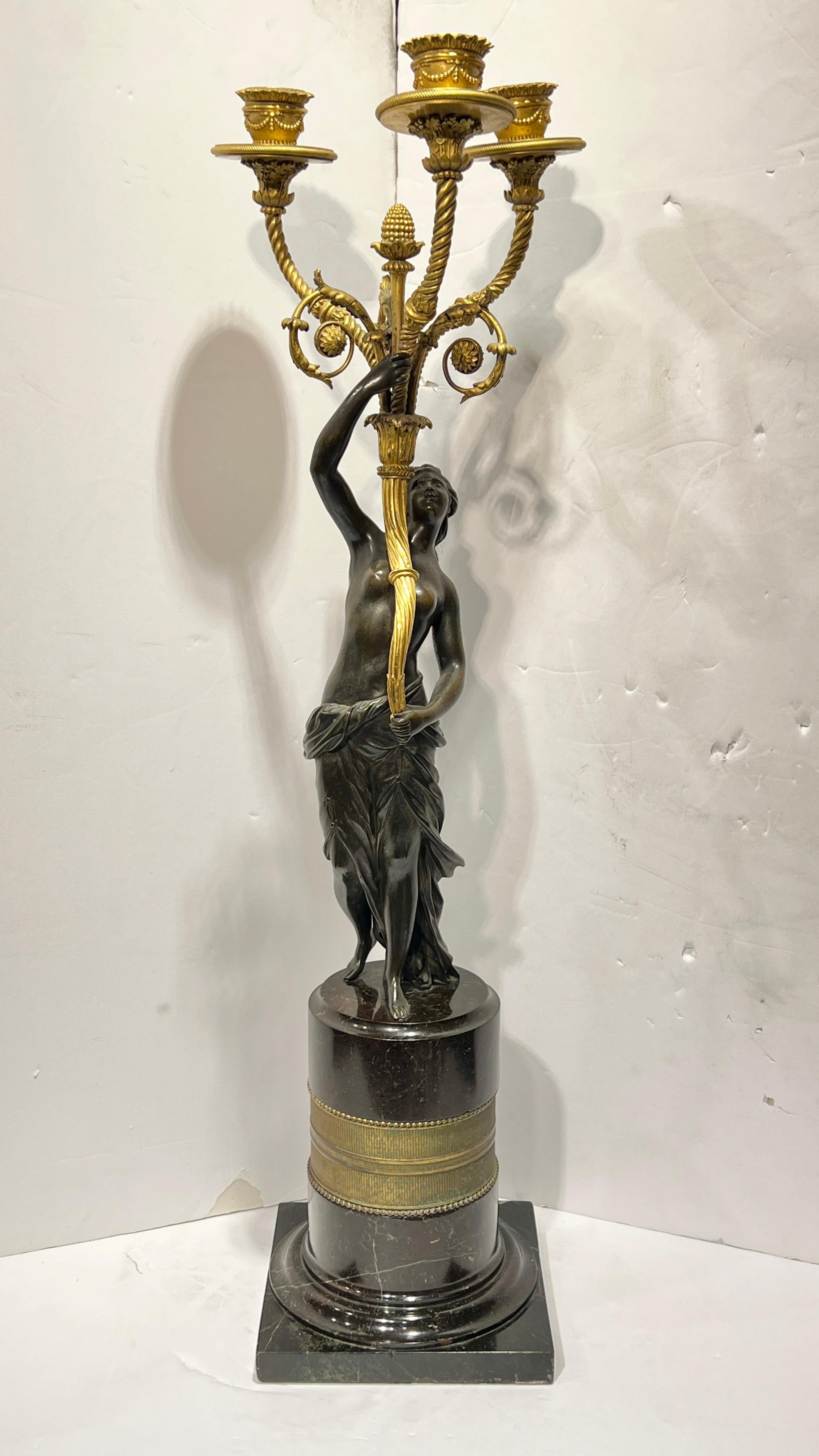 Pair of antique (19th century) French Louis XVI style figural patinated and gilt bronze three-light candelabra depicting neoclassical maidens, and mounted on unique dark variegated marble pedestals.  Each 27 inches tall and 6 inches wide/deep.