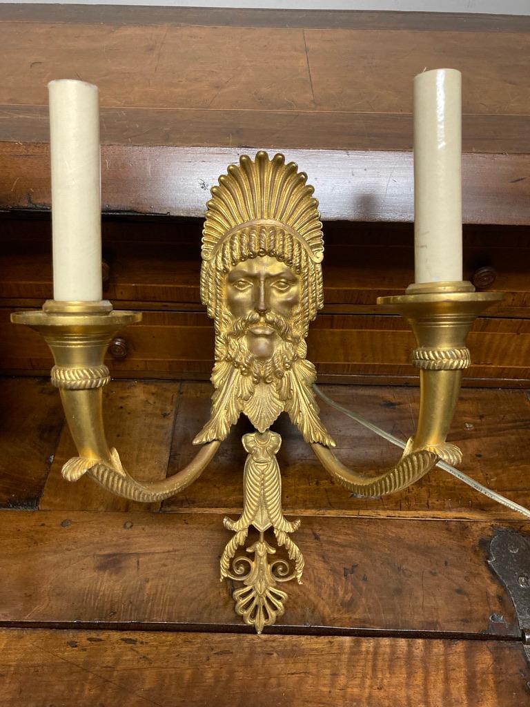 A very fine pair of bronze dore' neoclassical style two arm wall sconces with the head of a Roman or Greek bearded god. The beautifully cast and chased head crowned with an anthemion over curly locks and beard, with acanthus leaf decoration below. A