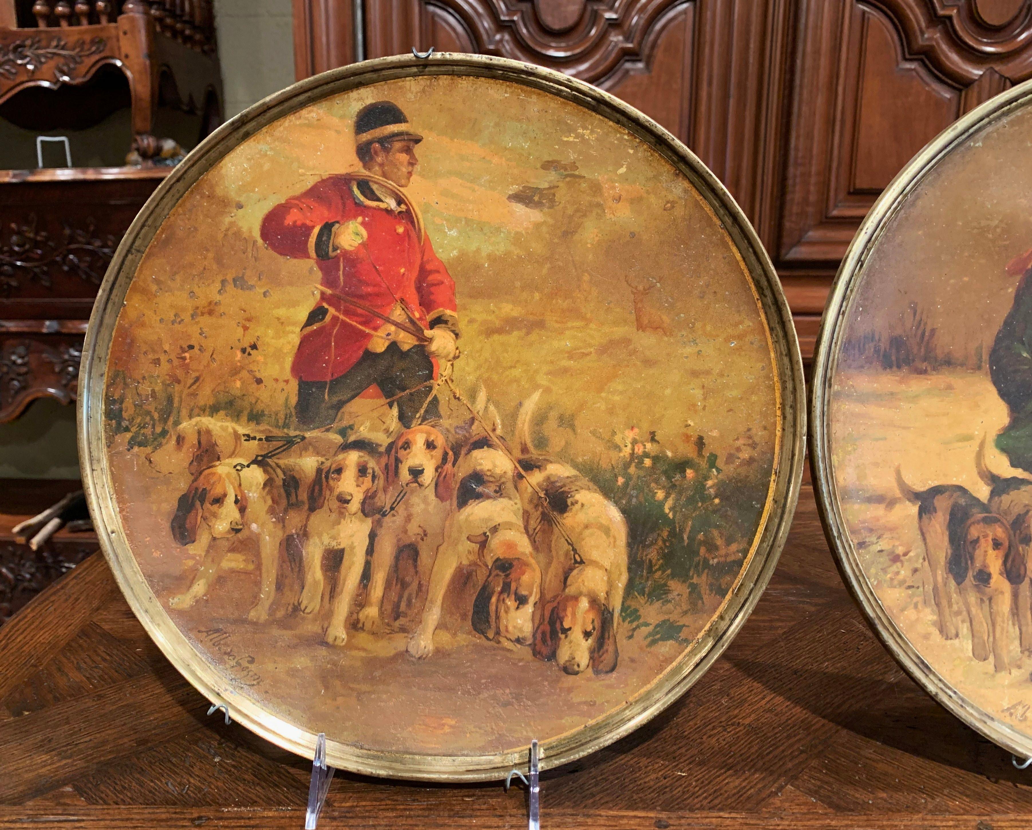 Bring color to a wall with this pair of antique hanging plaques. Created in France, circa 1880, each round metal plate with brass edge, depicts a hunt scene with hunter and dogs. Both art work are signed by the artist Albert de Gesne. The colorful