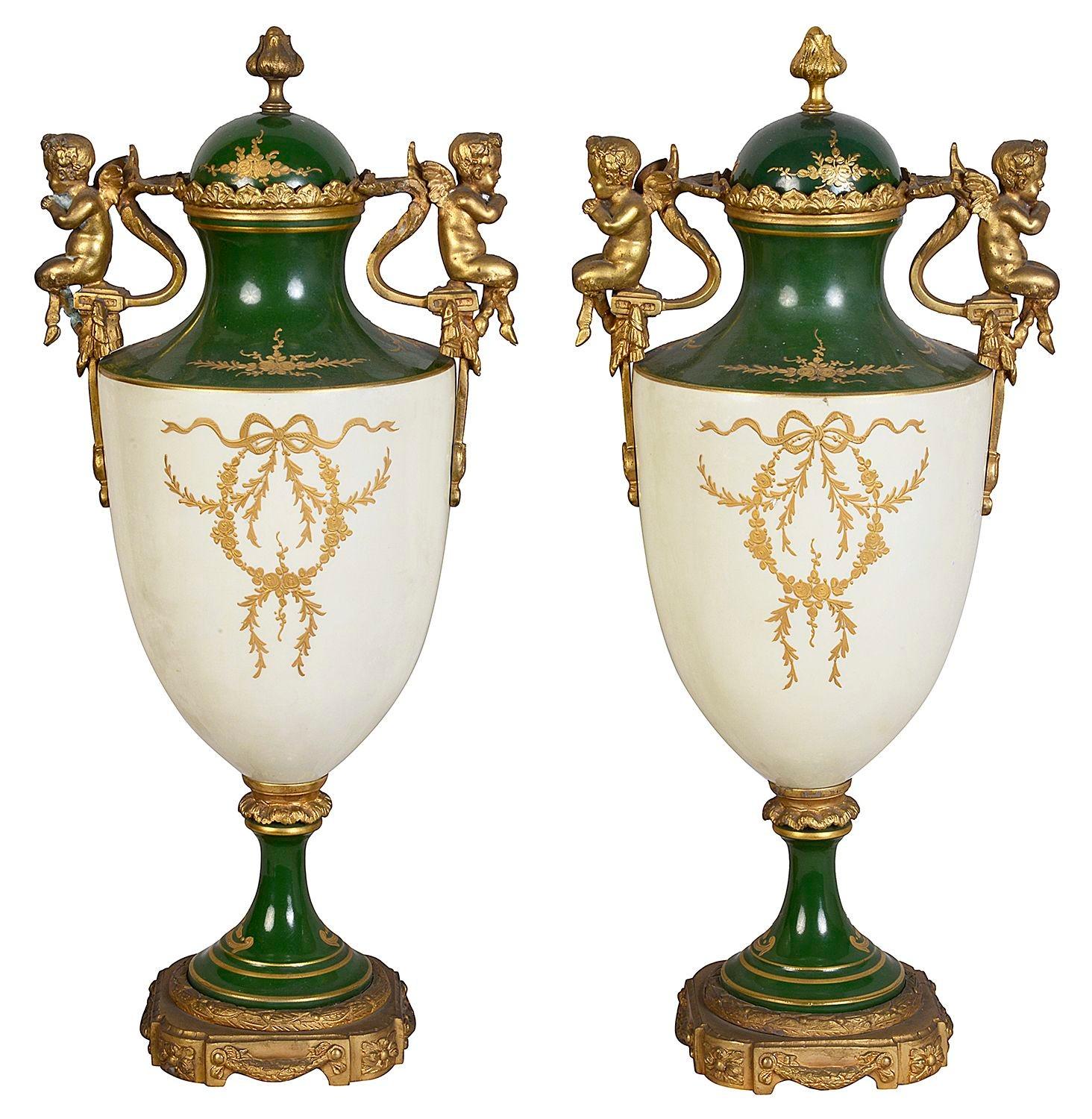 Coppia di vasi con coperchio in porcellana di Sèvres della fine del XIX secolo, ciascuno con un insolito fondo verde, decorazioni dorate a volute, due manici a cherubino su ciascuno, scene dipinte a mano raffiguranti fanciulle classiche sedute con